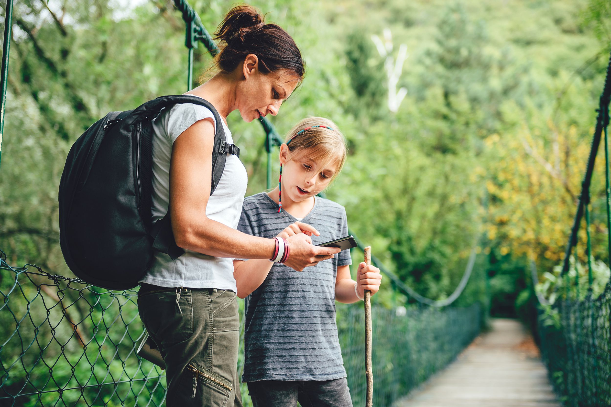 Mother and daughter looking at phone and hiking in the forest