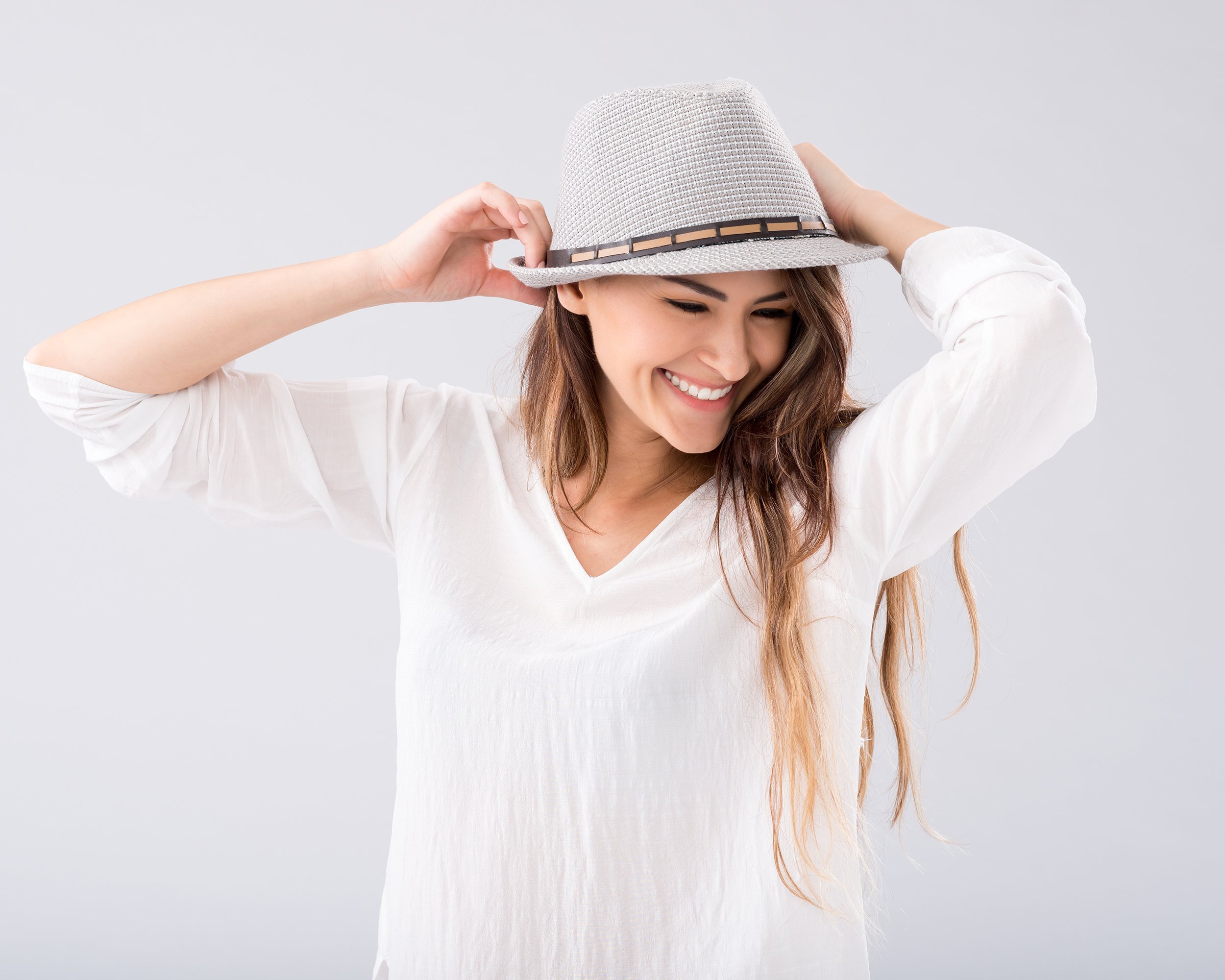 young woman laughing while wearing a fedora