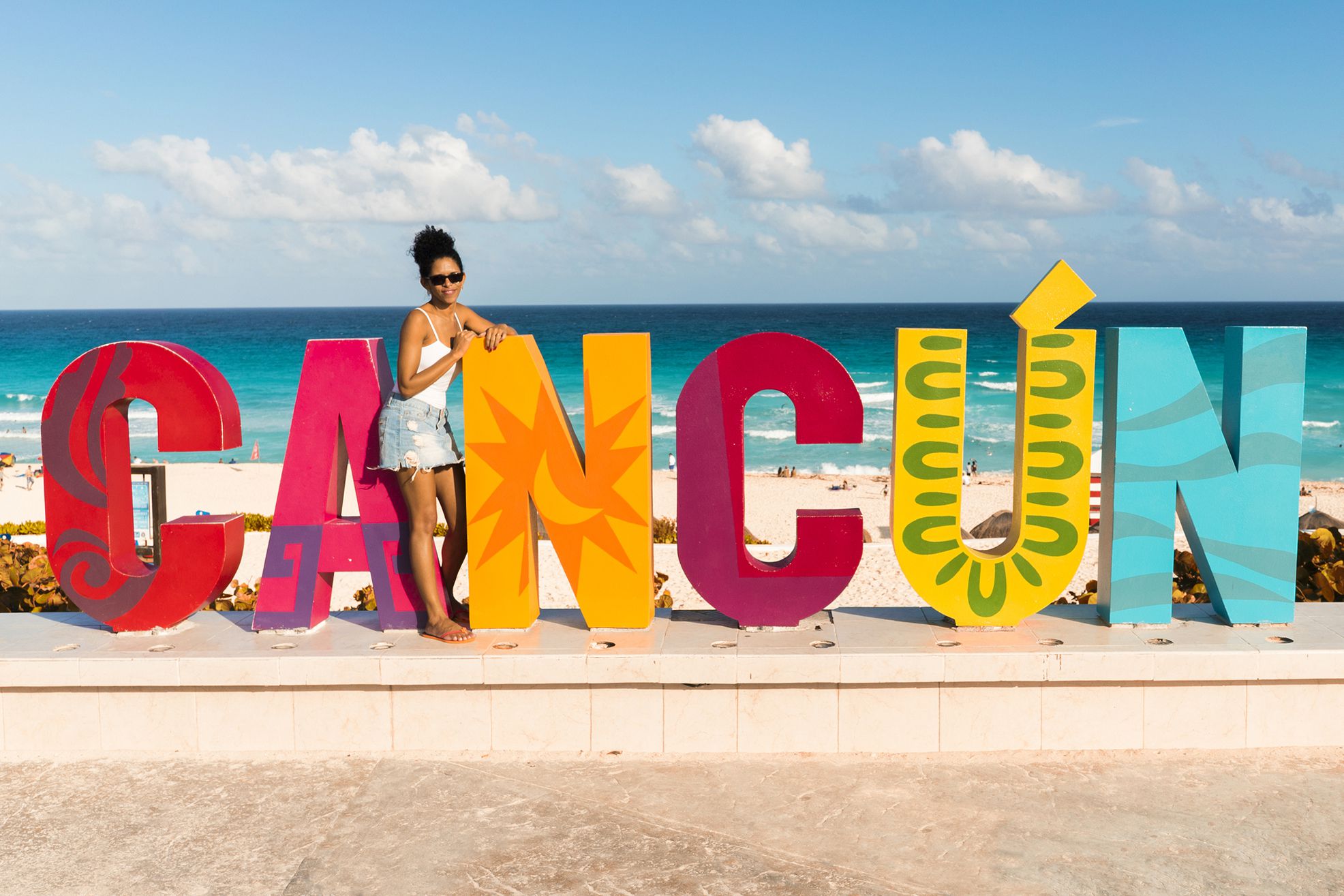woman standing in front of giant cancun letters on beach