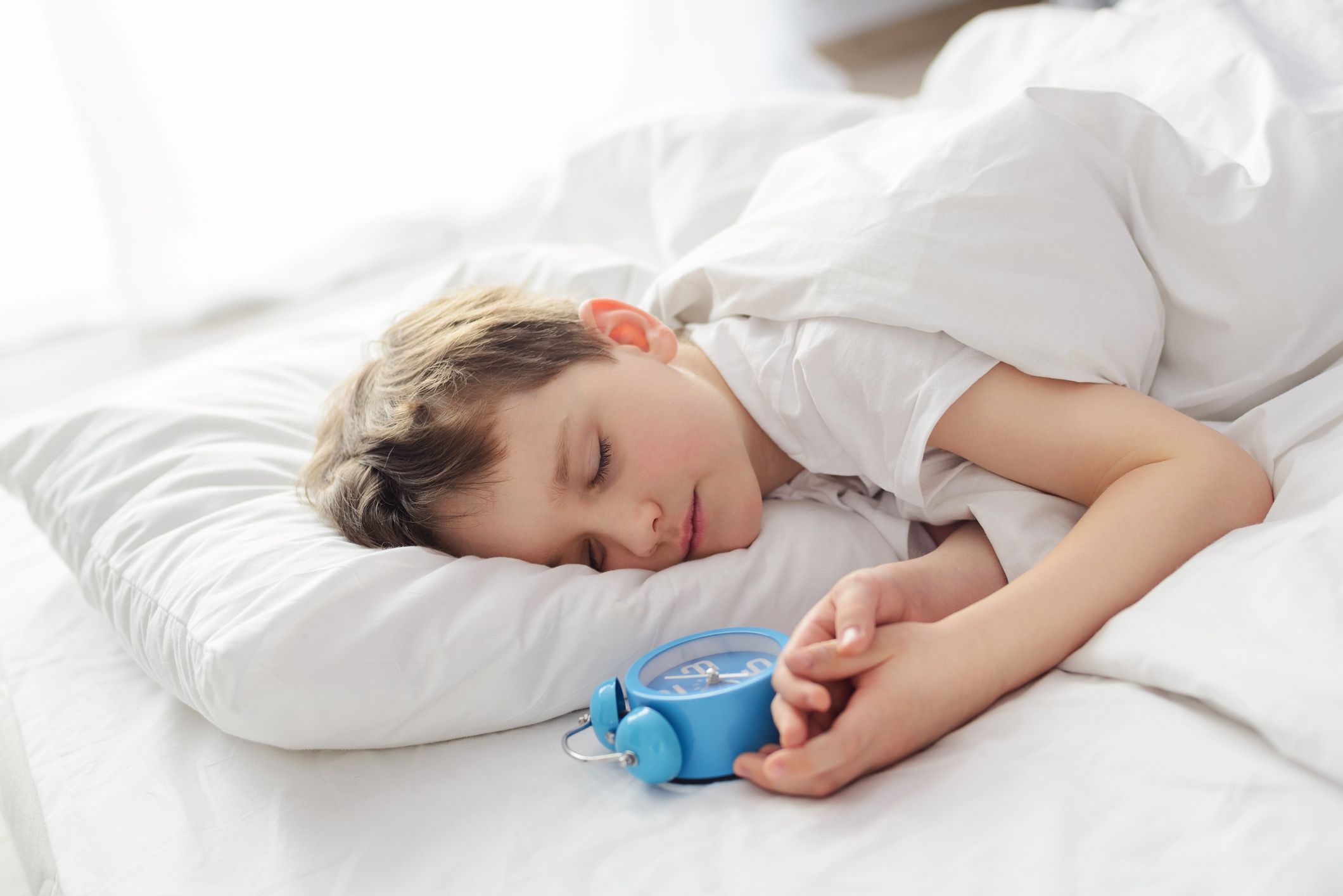 child sleeping peacefully next to alarm clock