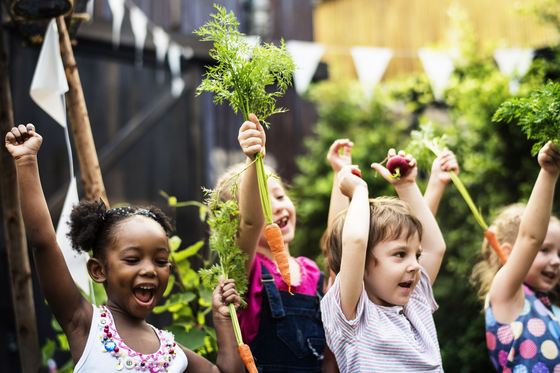 happy children holding up carrots in garden
