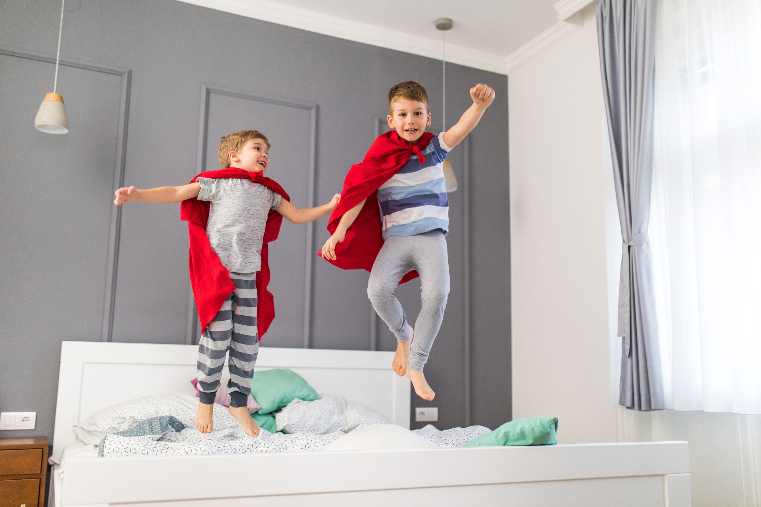 two boys jumping on their bed