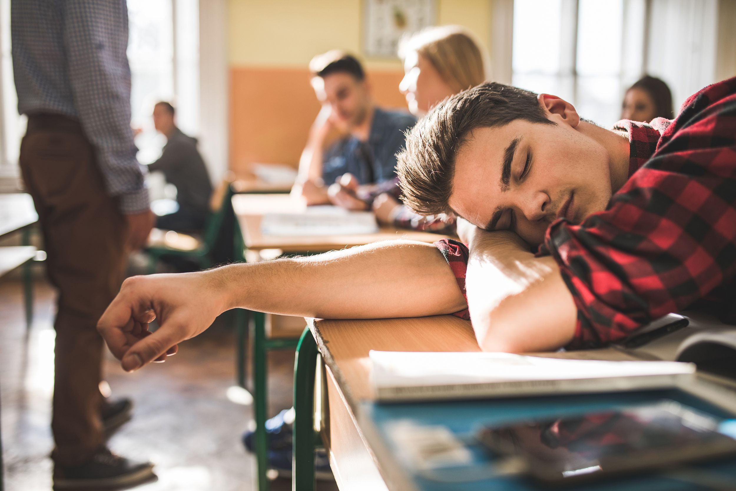 tired teenage boy napping at school during the class