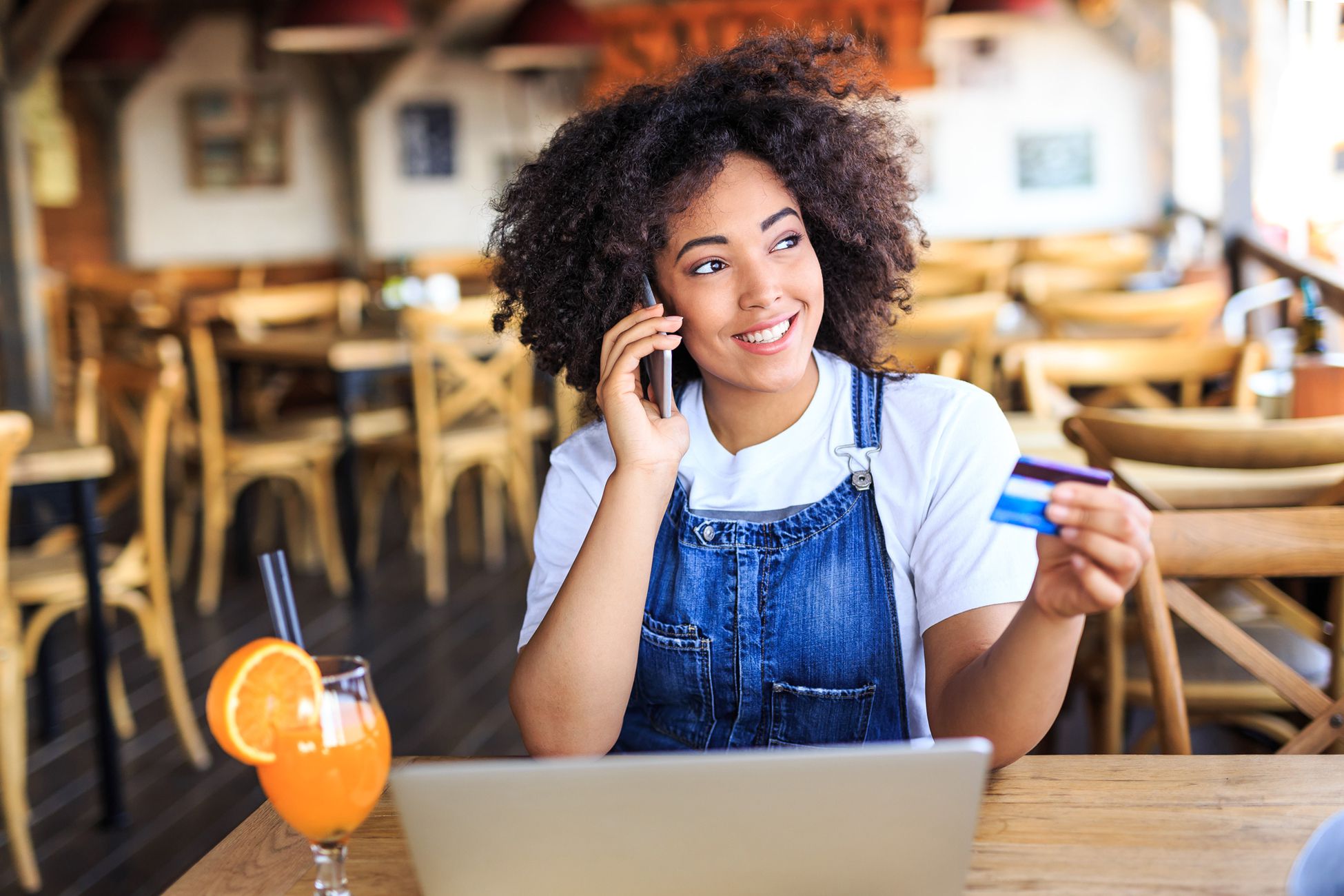 smiling woman holding credit card talking on phone