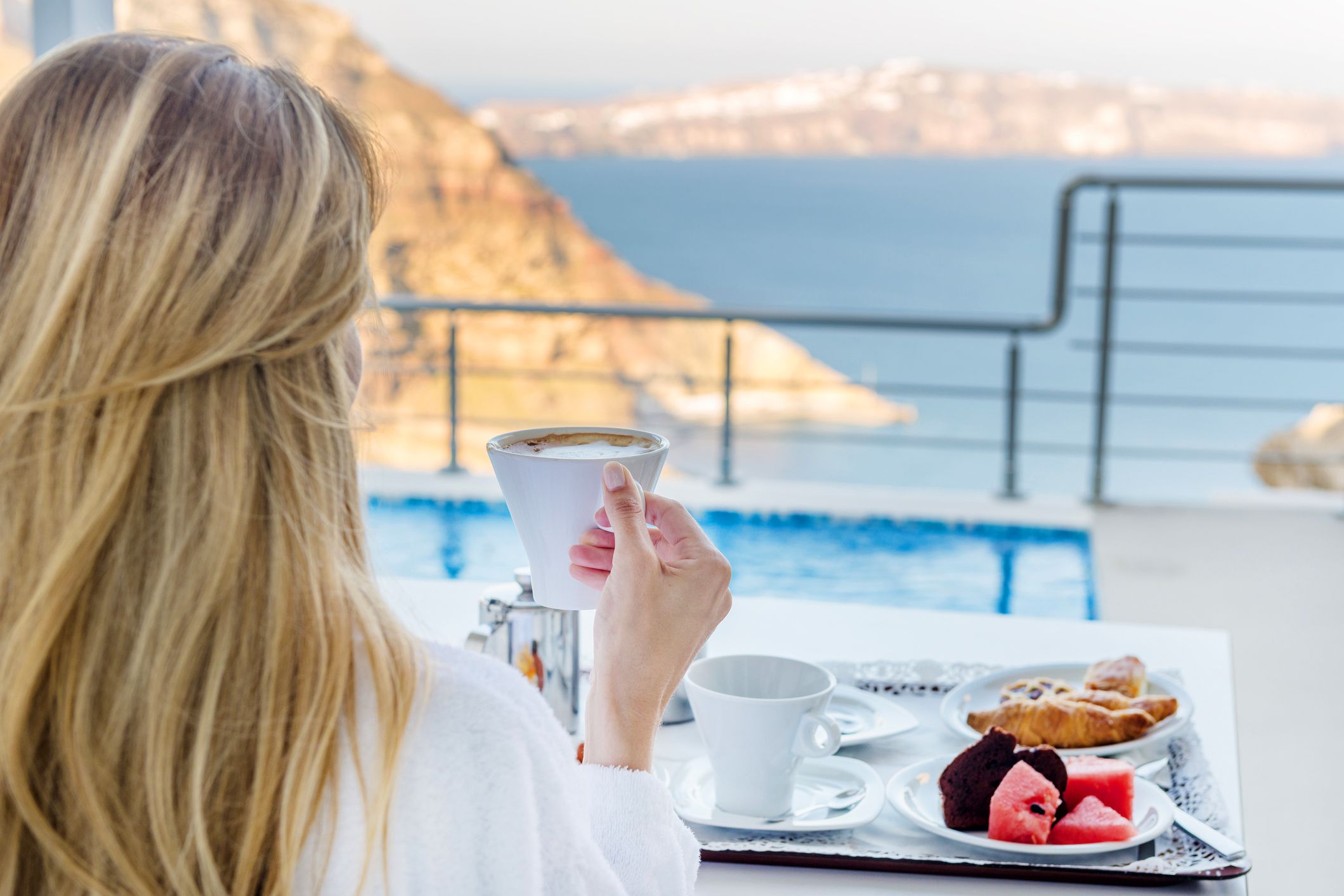 woman eating hotel breakfast tray with ocean in distance