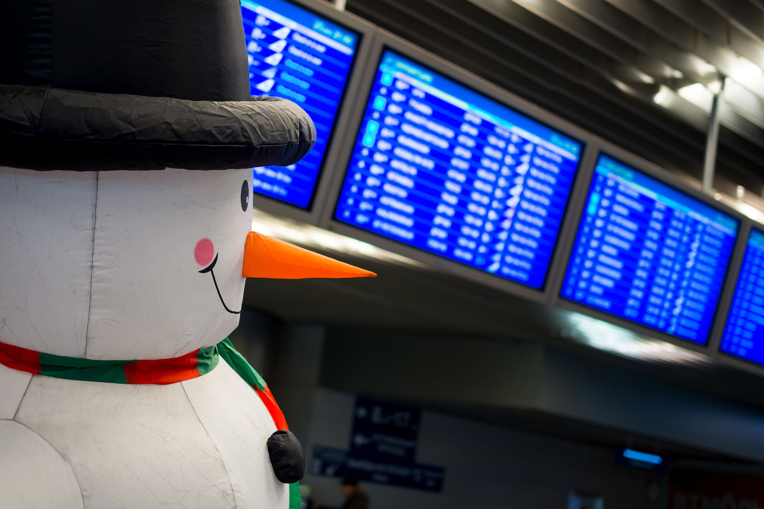 Inflatable snowman in an airport in front of flight schedules