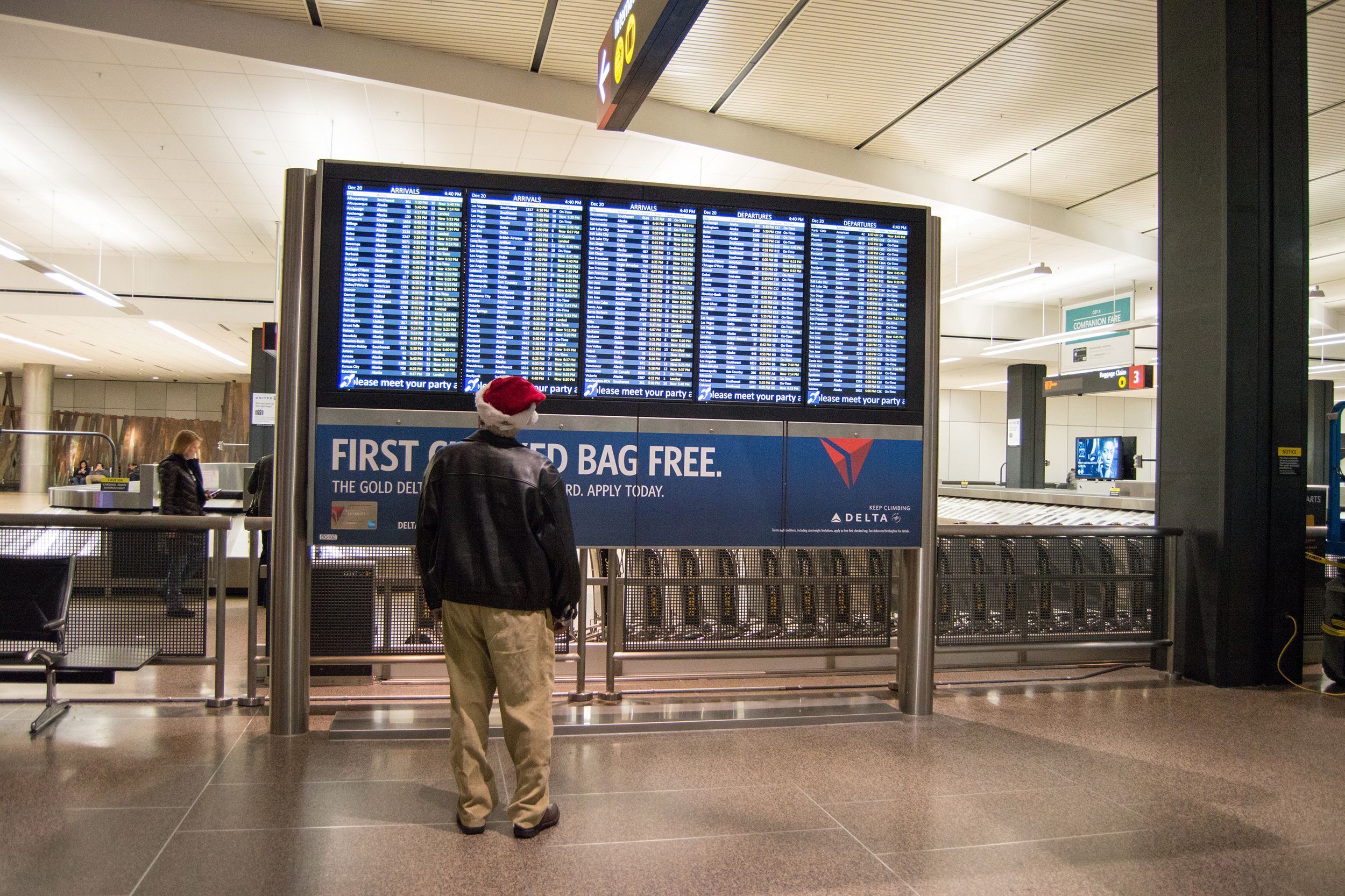 Man wearing a Santa hat looking at flight schedules