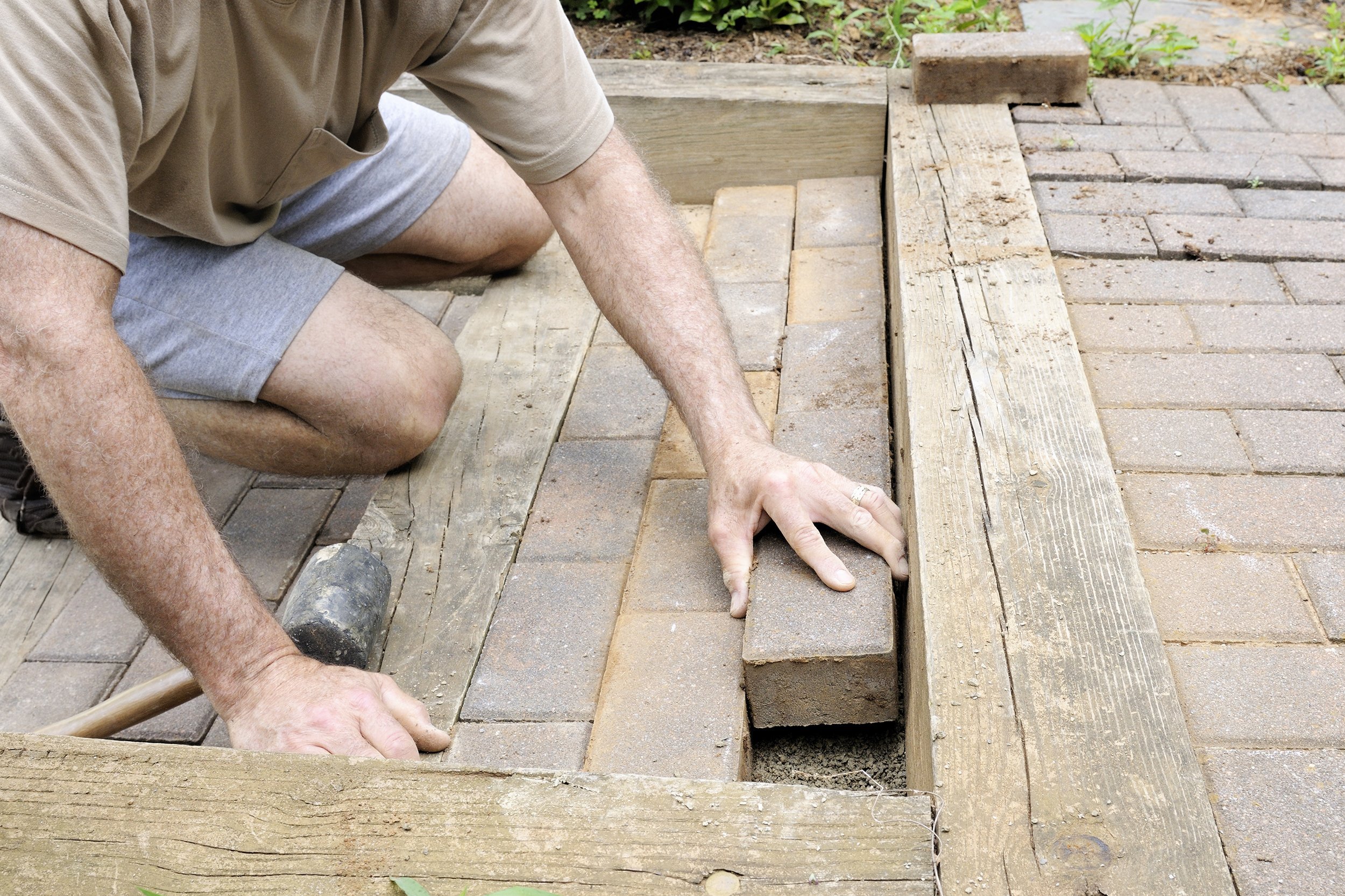 worker installing bricks in walkway