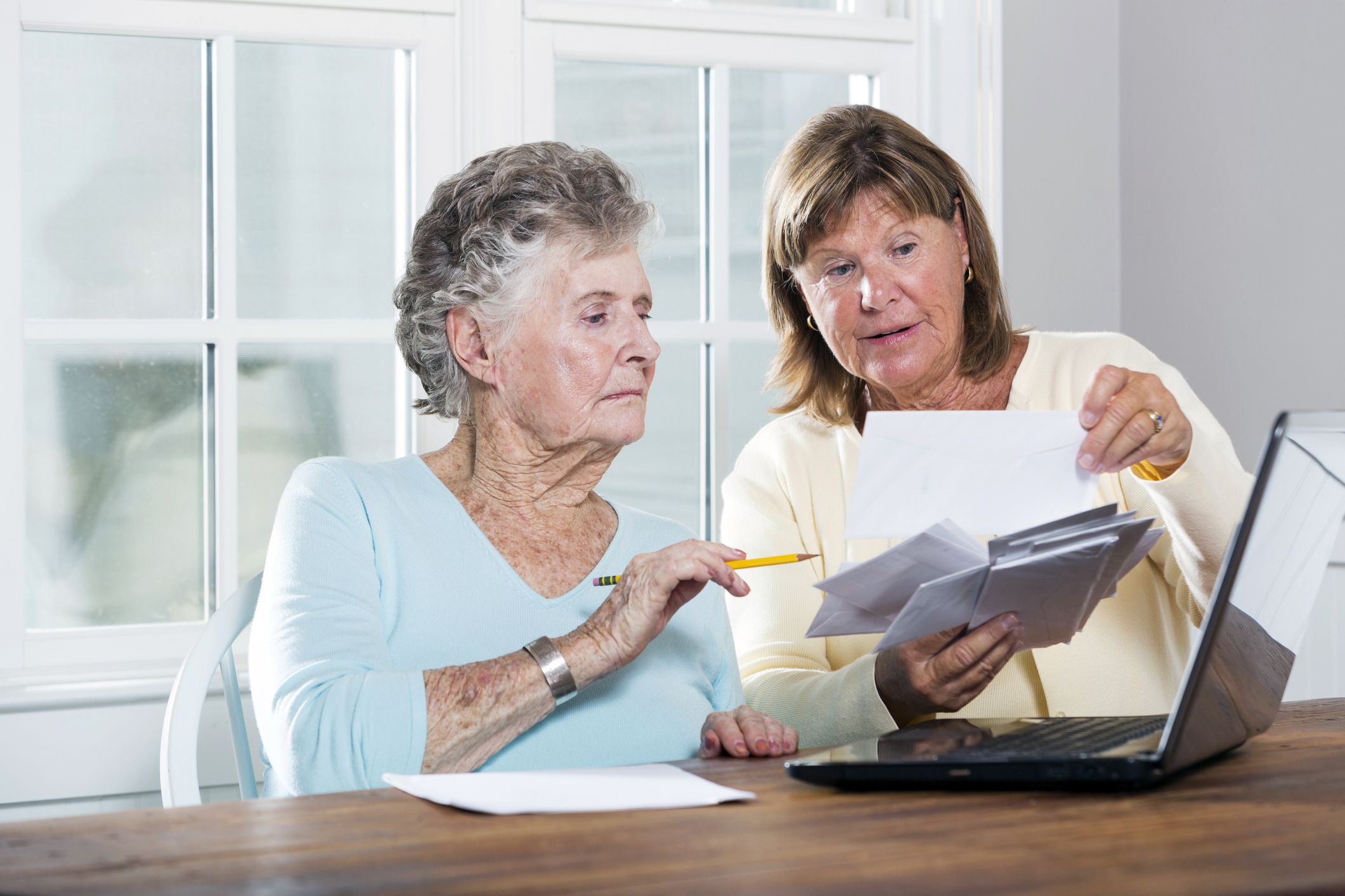 elderly woman and middle-aged woman reviewing letters and checks