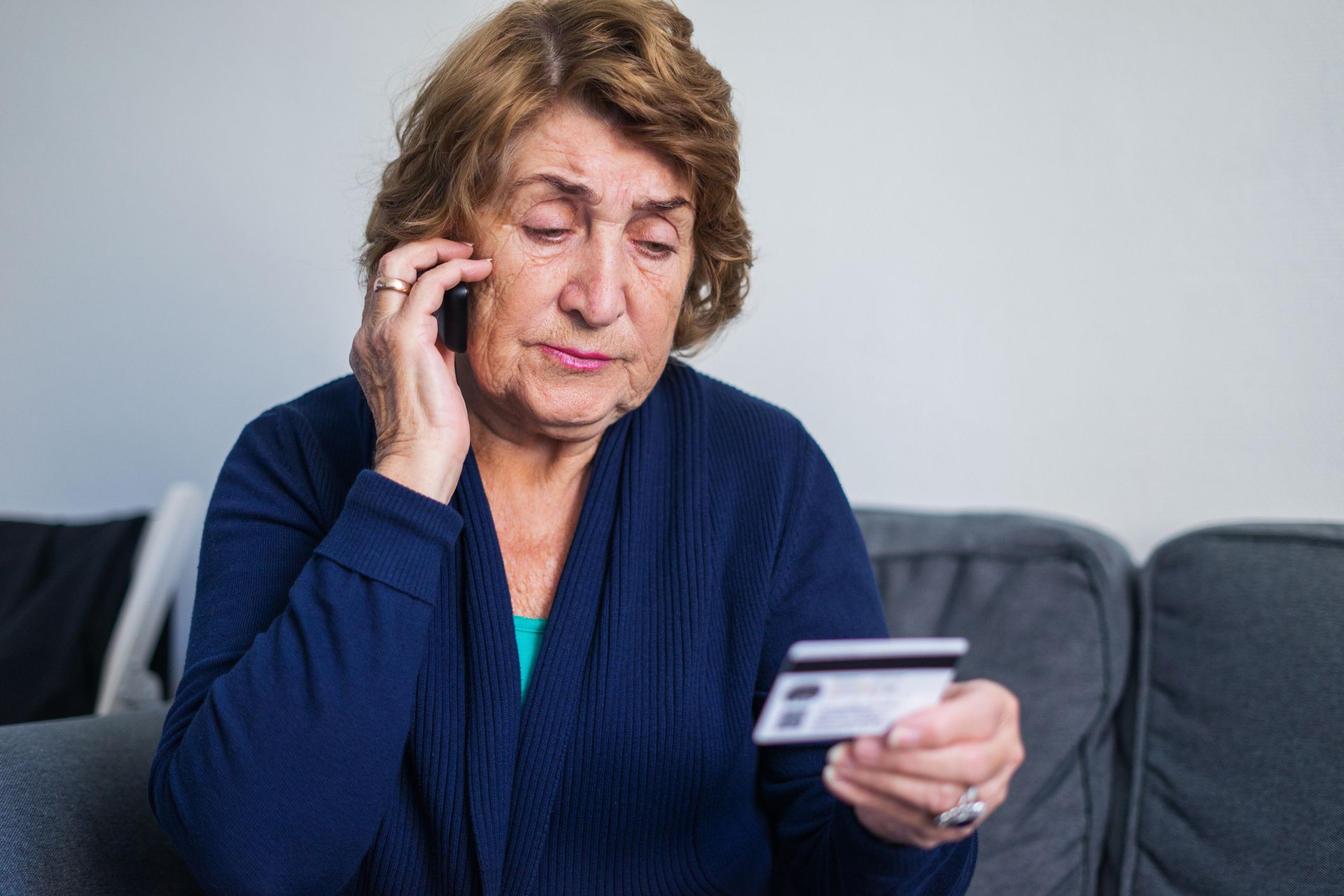 senior woman on the phone while holding credit card