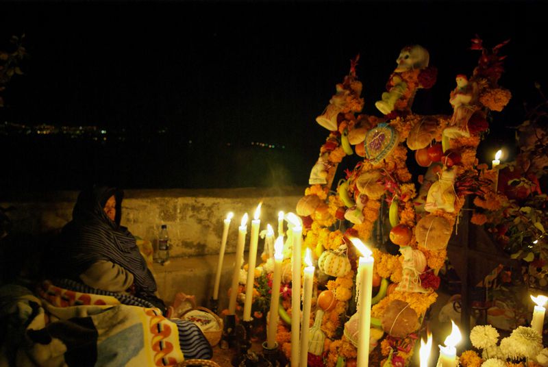 A woman holds a lat night vigil to celebrate Dia de los Muertos