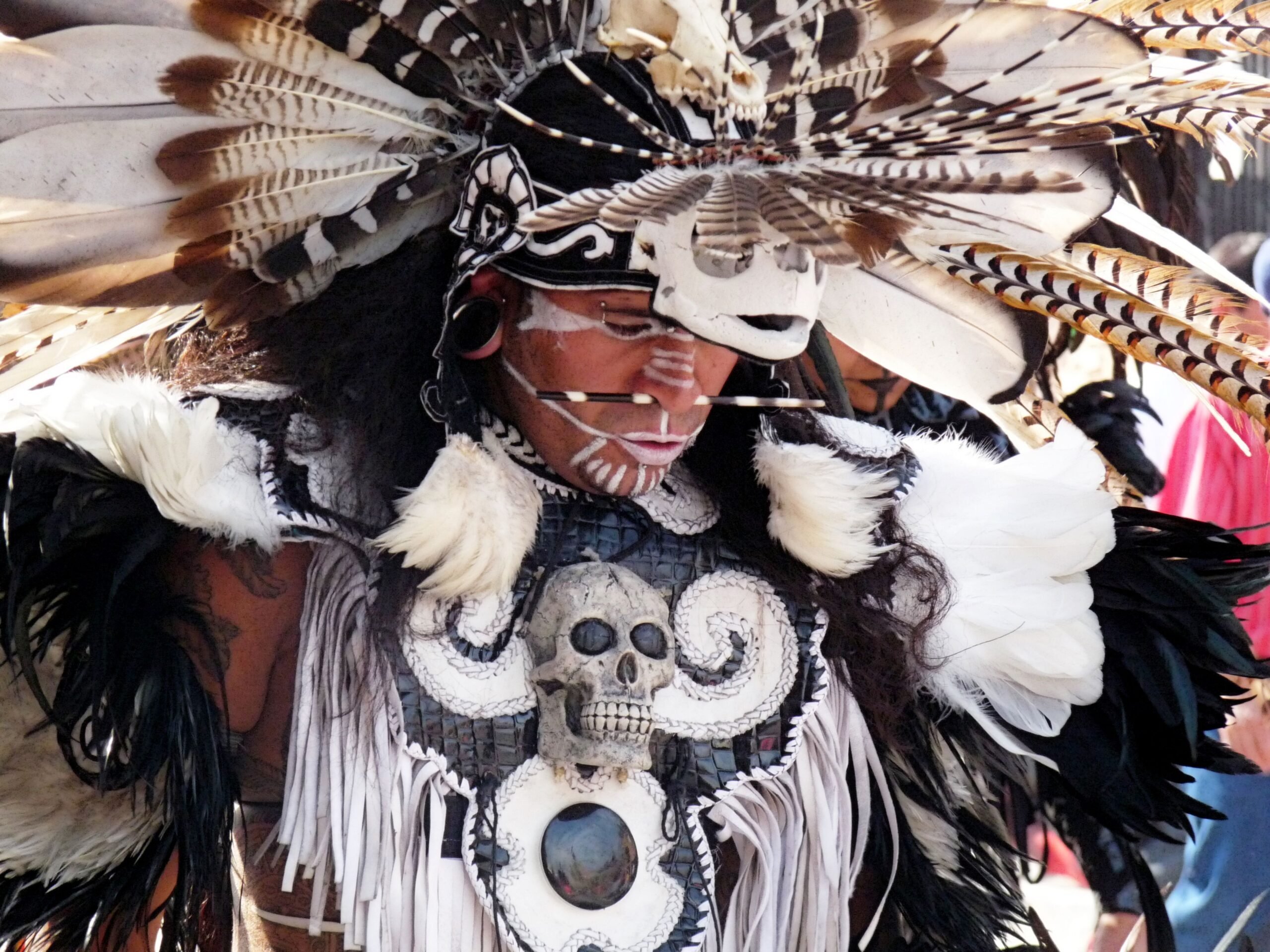 Man wearing elaborate head dress of feathers and skulls to celebrate Dia de Meurto