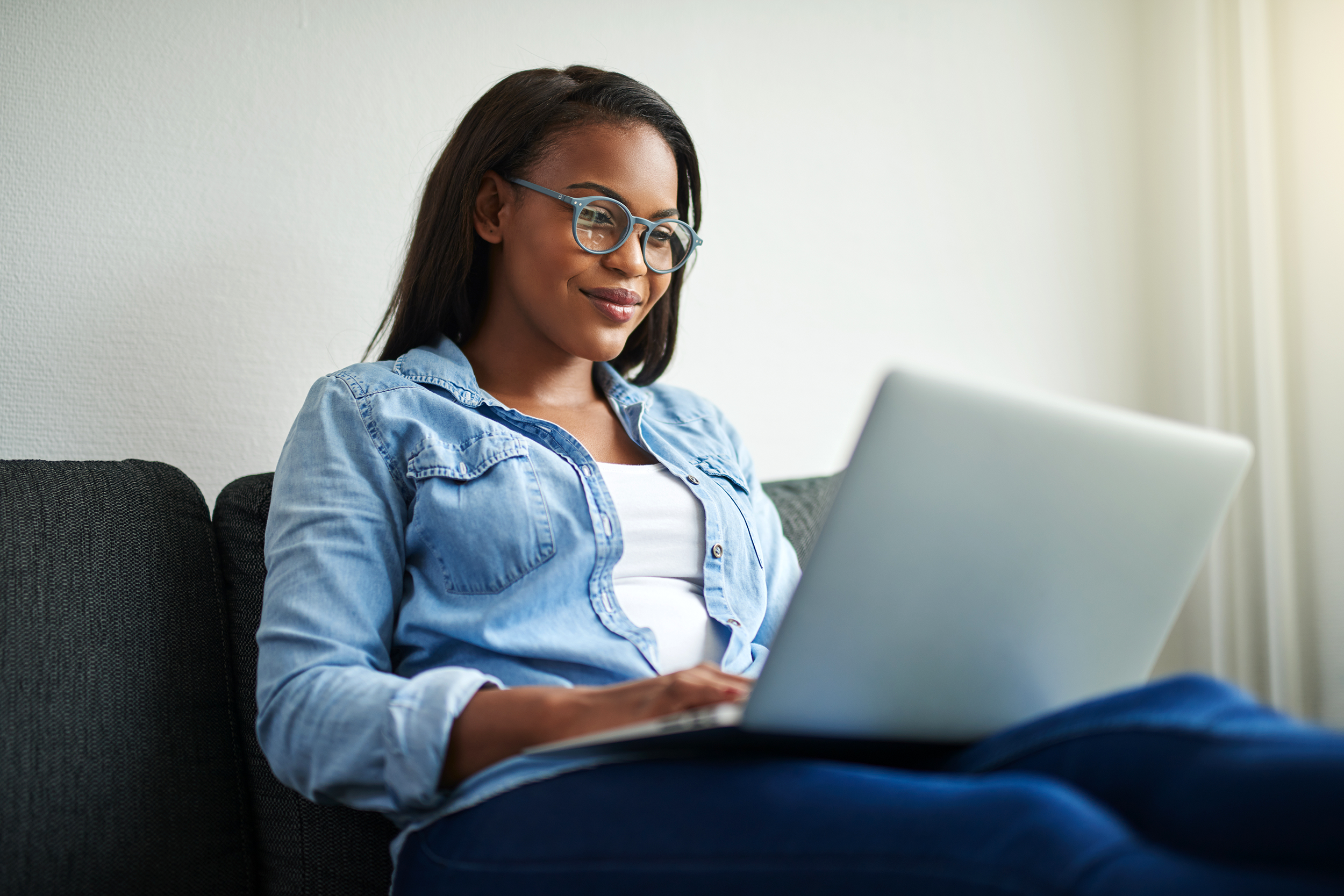 Woman on her couch using her laptop