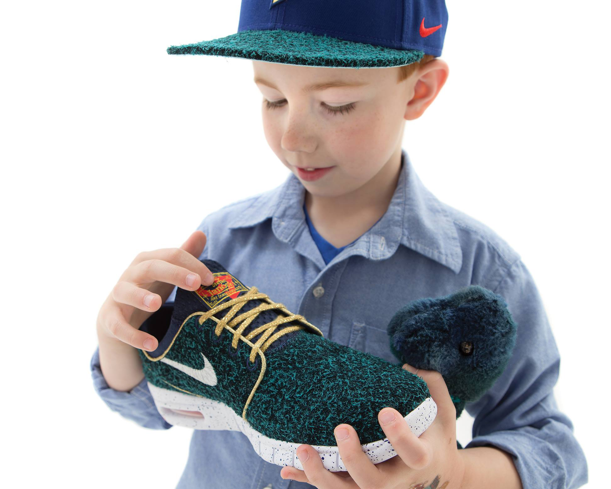 Little boy wearing a Nike hat and holding Nike shoes