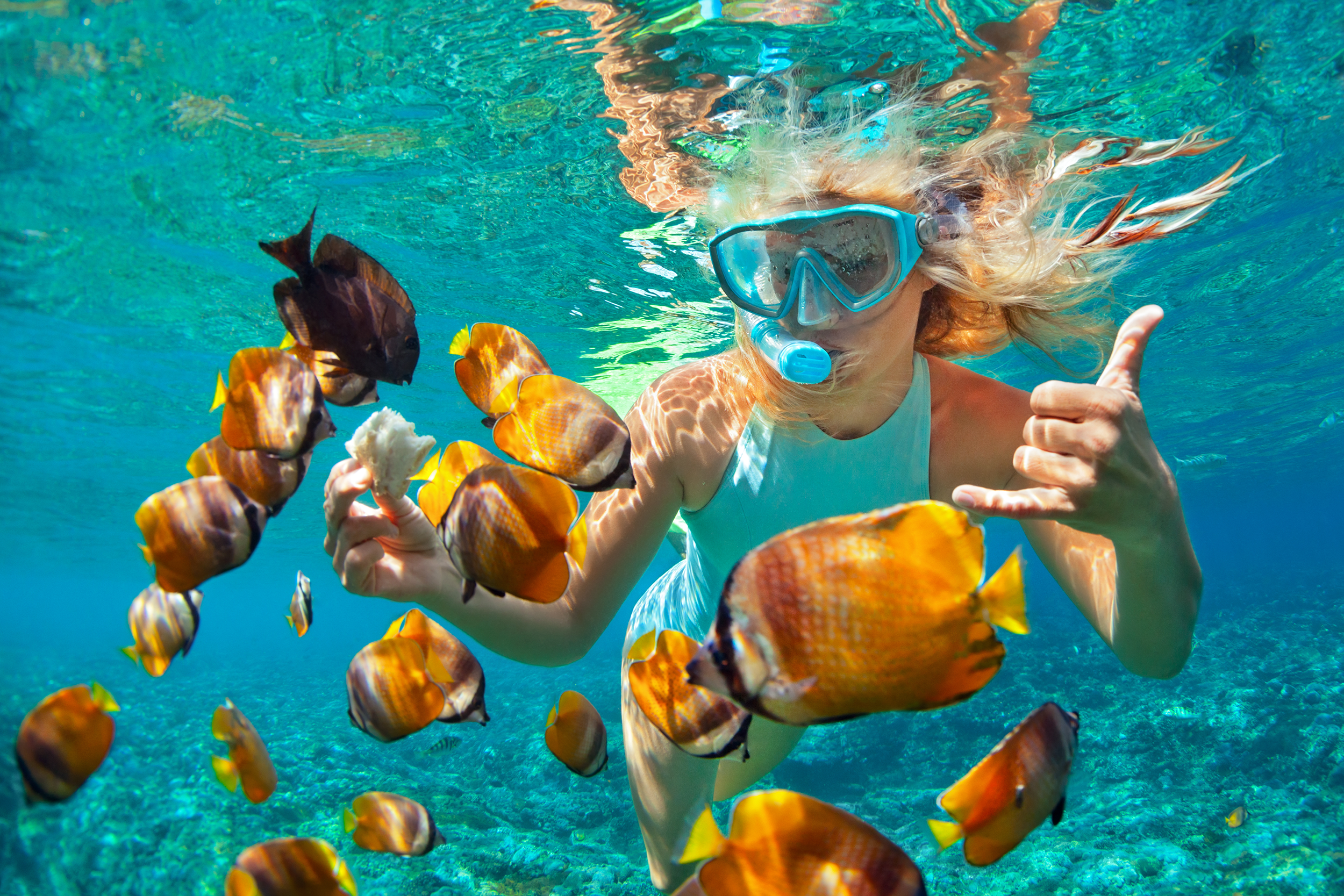 Woman snorkeling with orange fish around her
