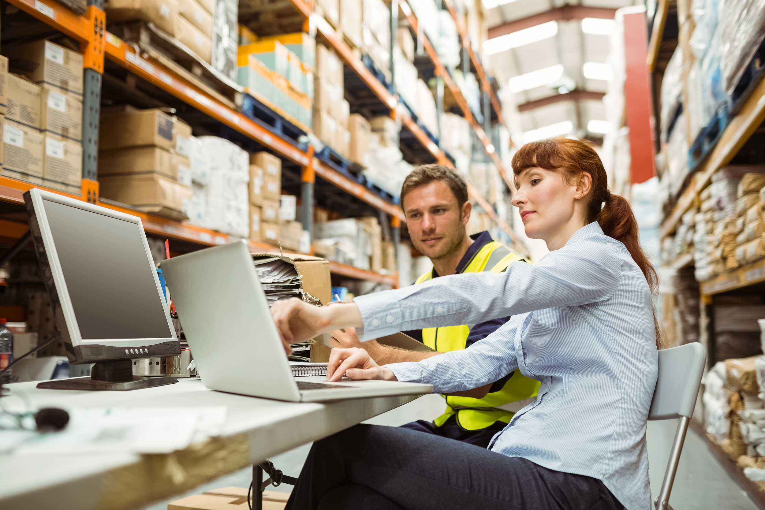People in a warehouse looking at their laptops