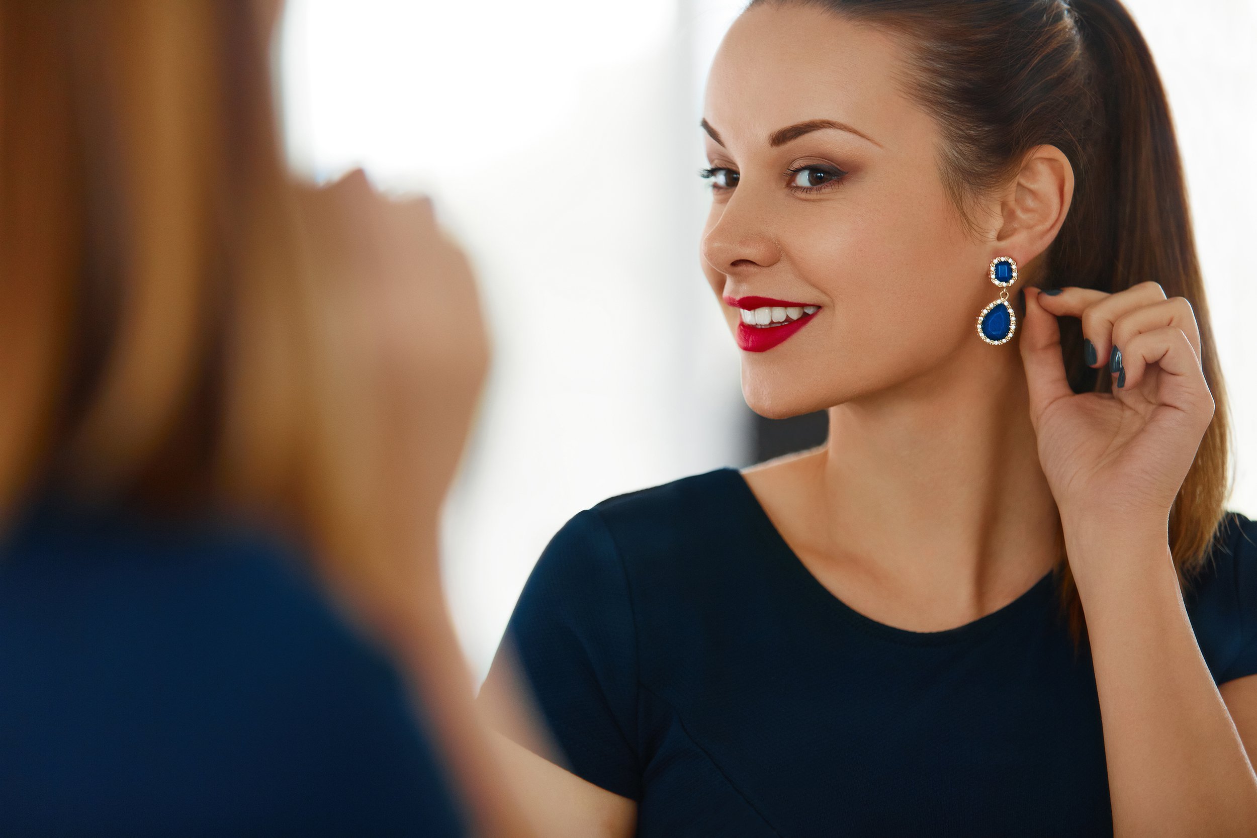 woman looking in mirror, at her earrings