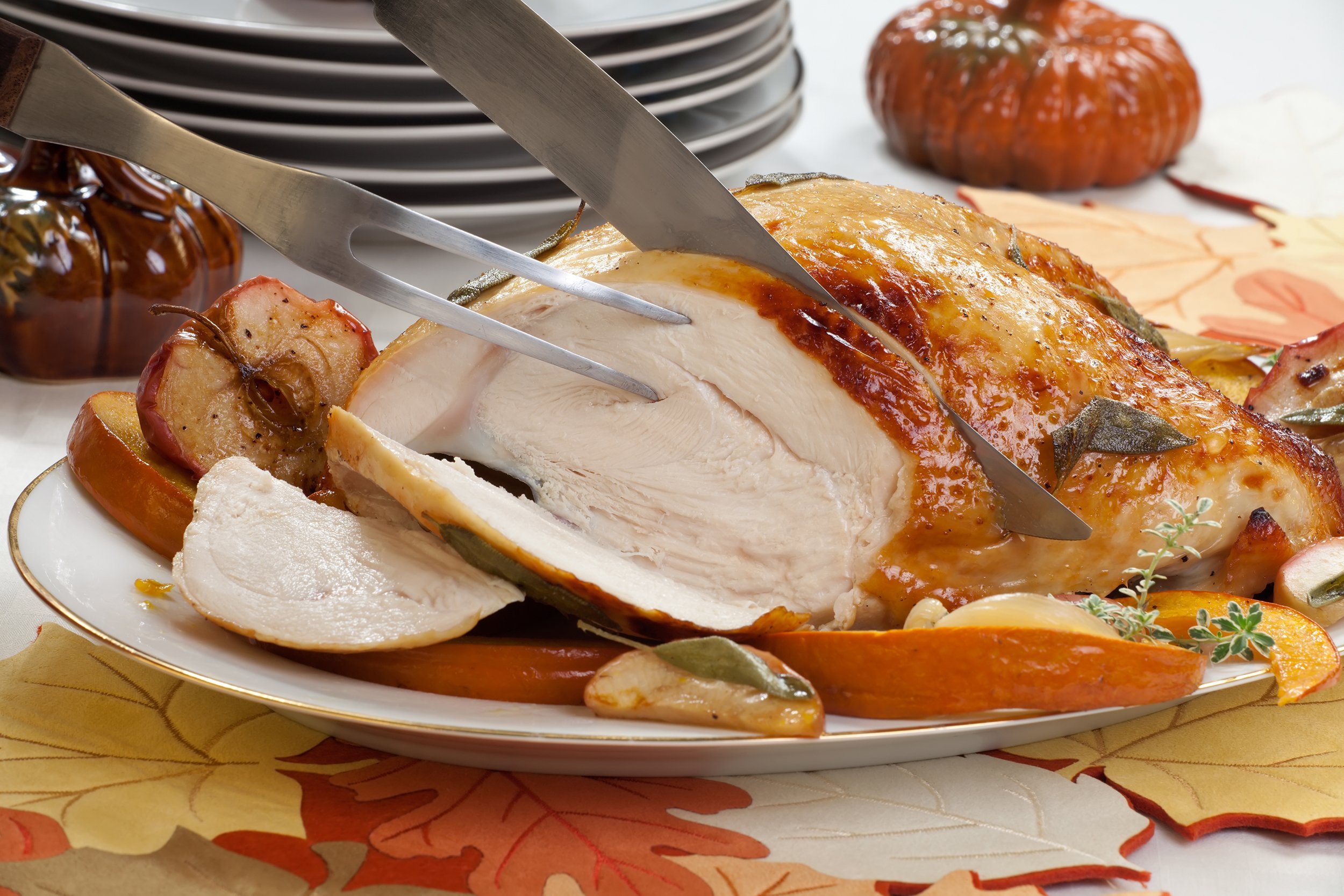Knife carving a roasted turkey breast