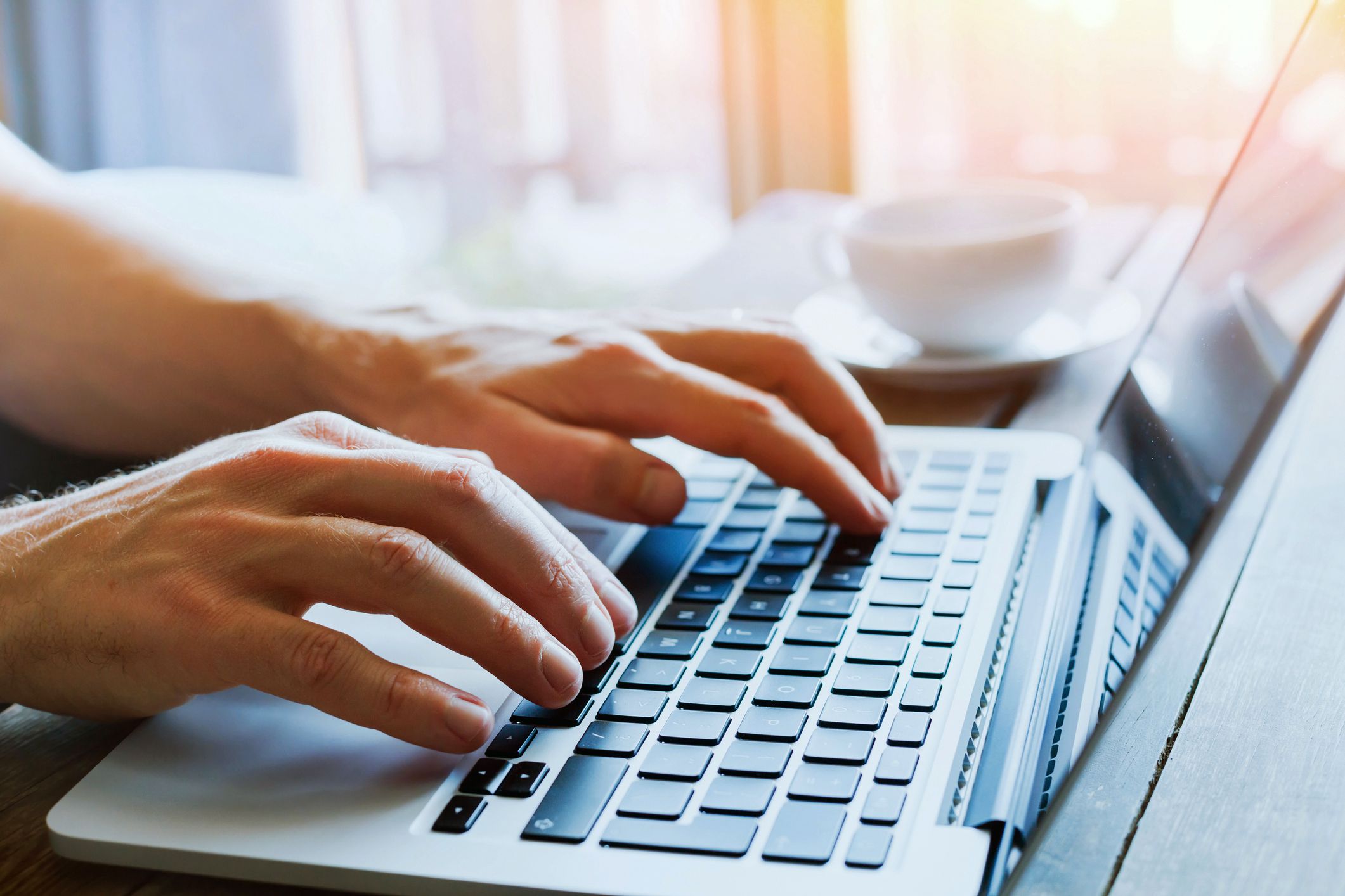 close-up of hands typing on laptop