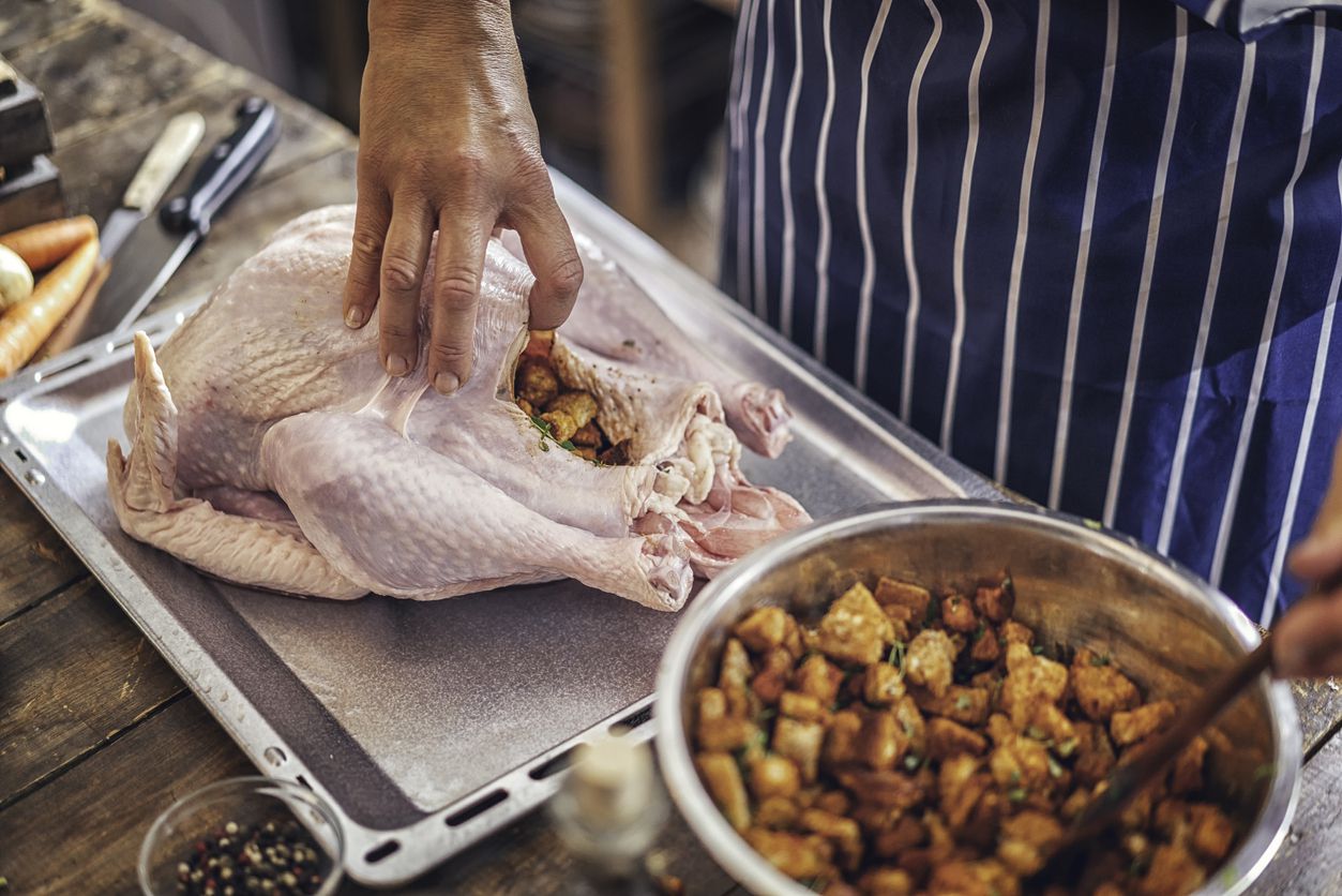 hands putting stuffing in raw turkey