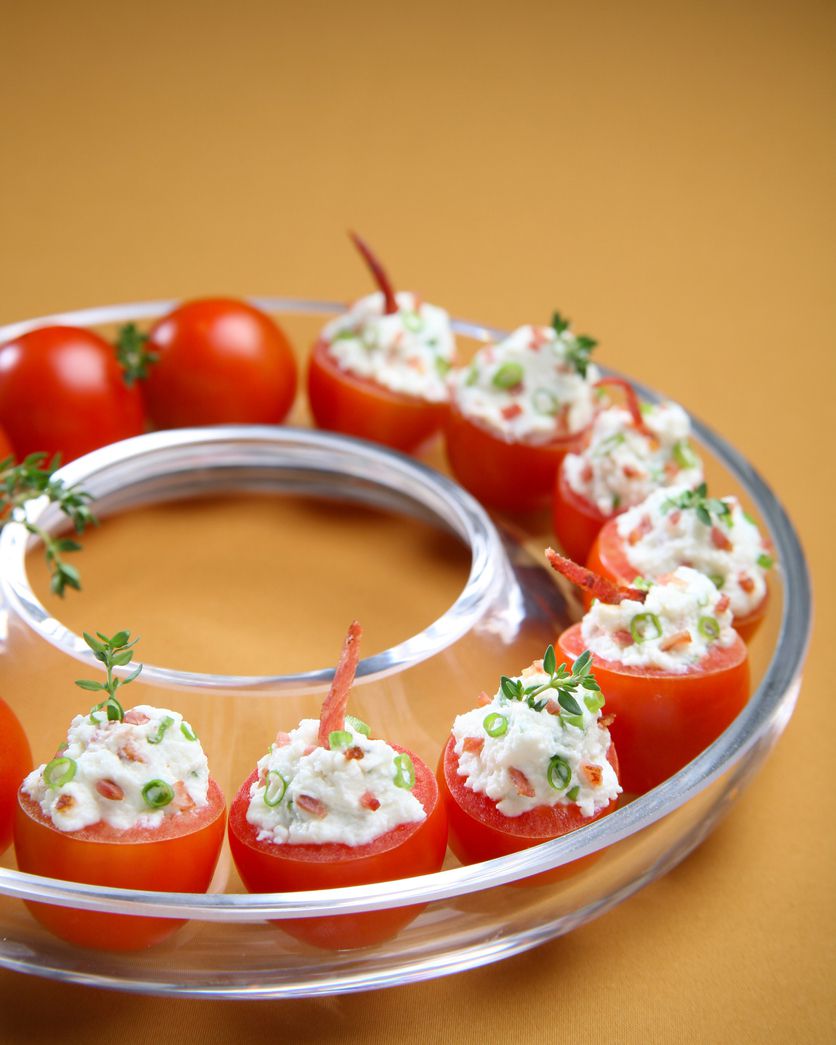 stuffed cherry tomatoes in circular glass dish on wooden surface