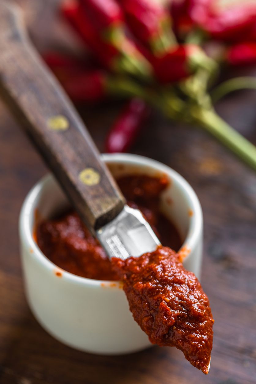 harissa on knife with peppers in background