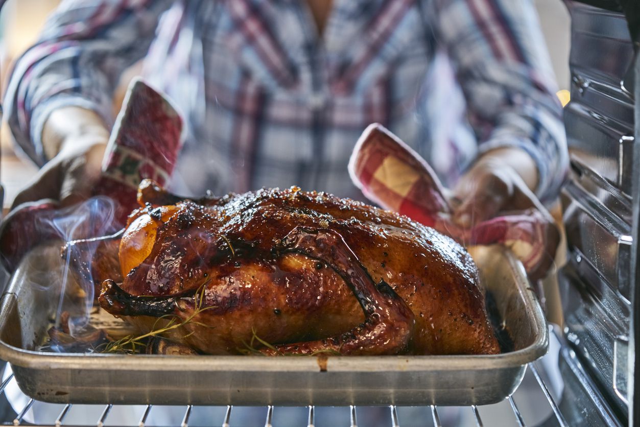 person taking roast duck out of oven