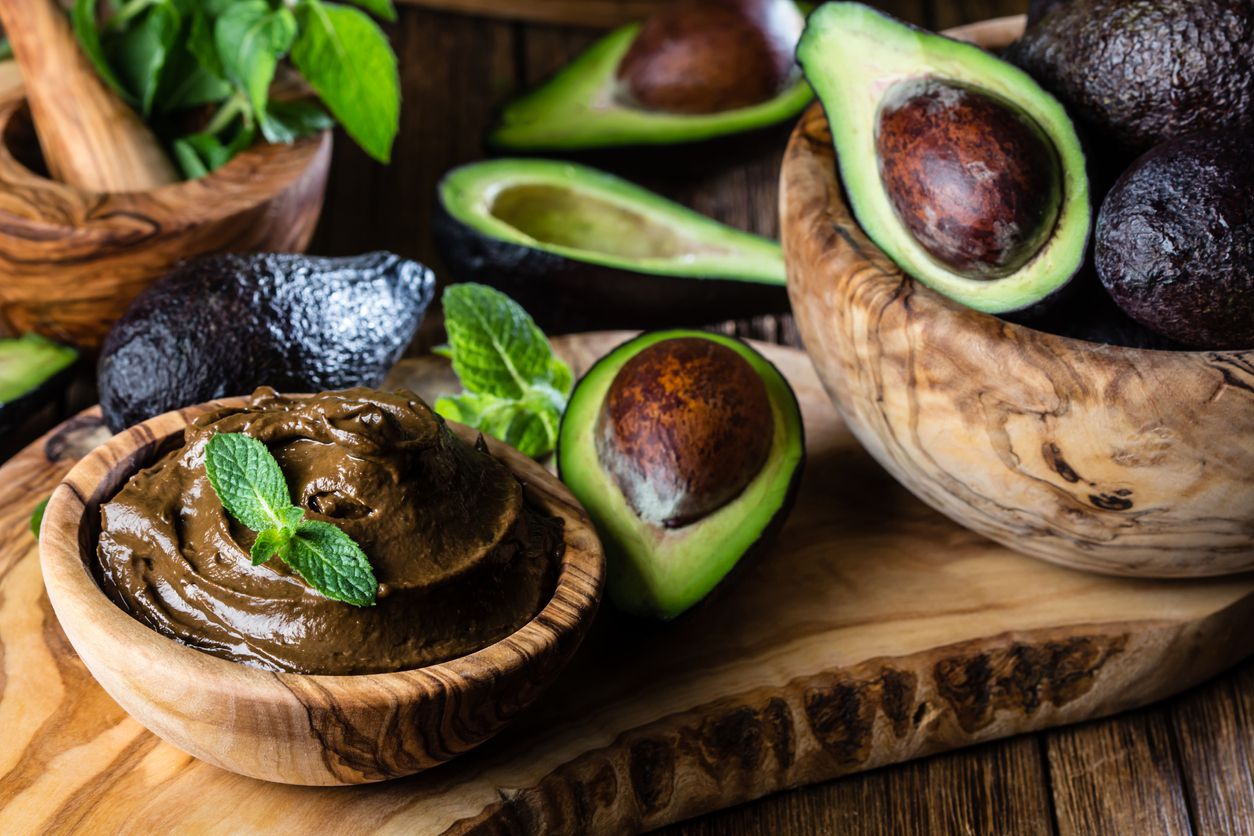 avocado cacao mousse in wooden bowls with avocados