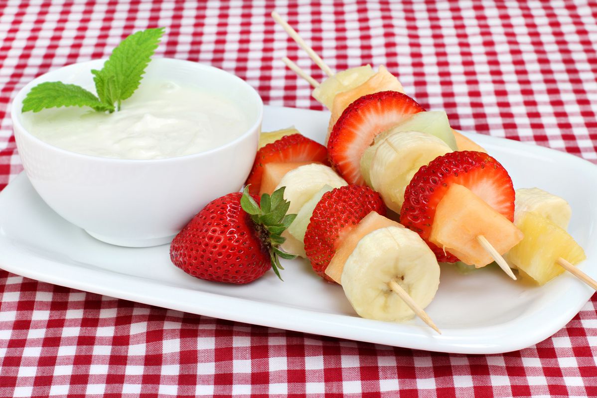 yogurt and fruit kebabs on red gingham surface