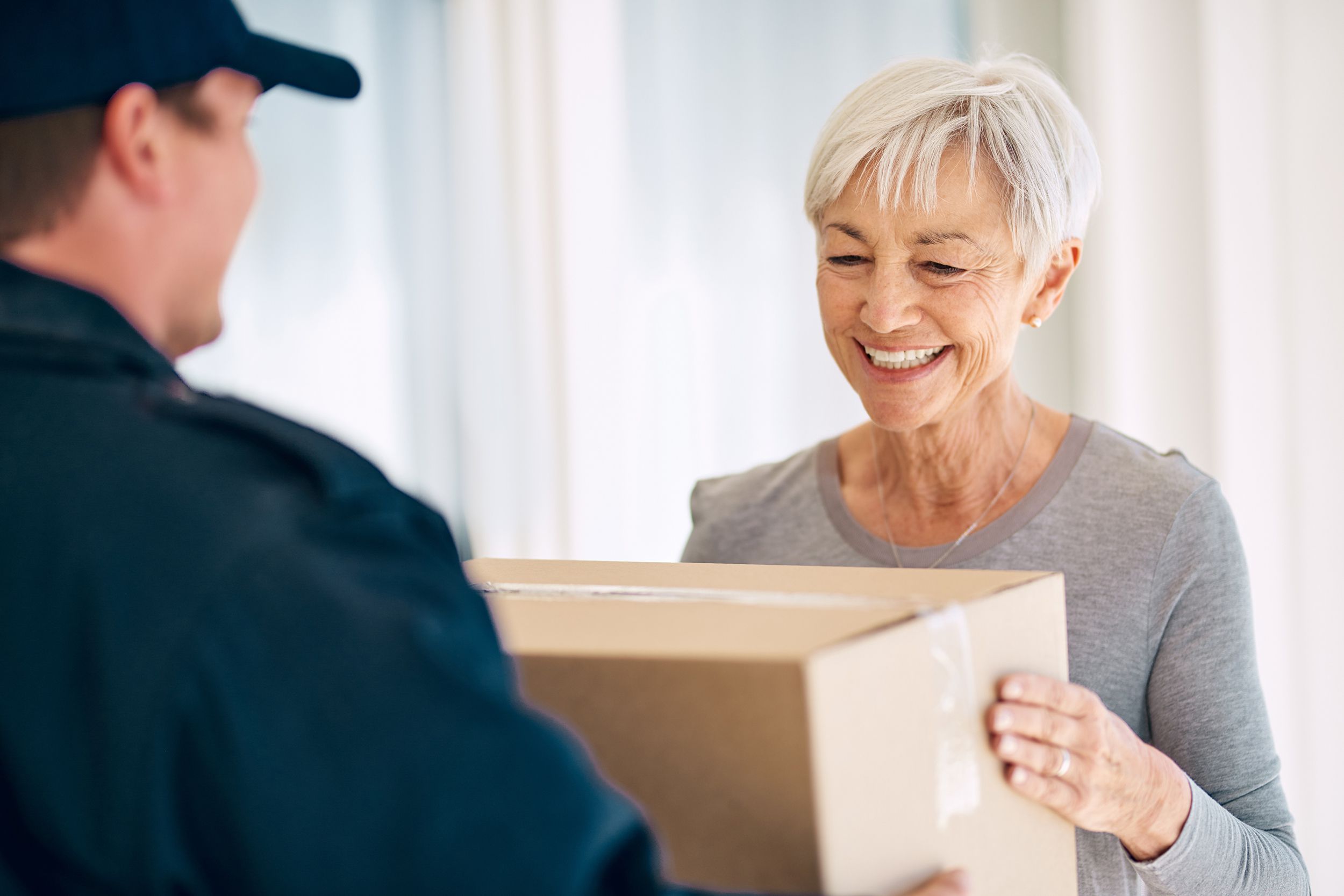 happy senior receiving box from delivery person