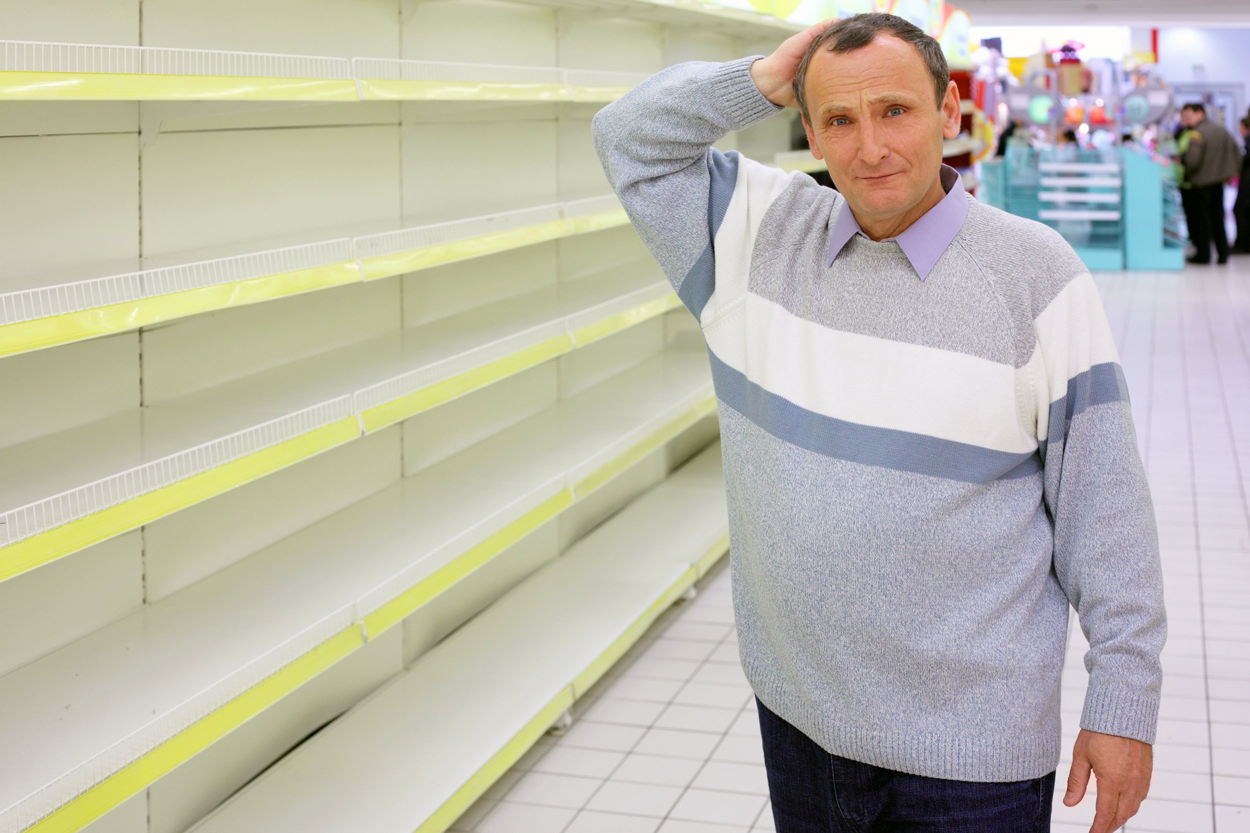 Older man standing in a store with empty shelves