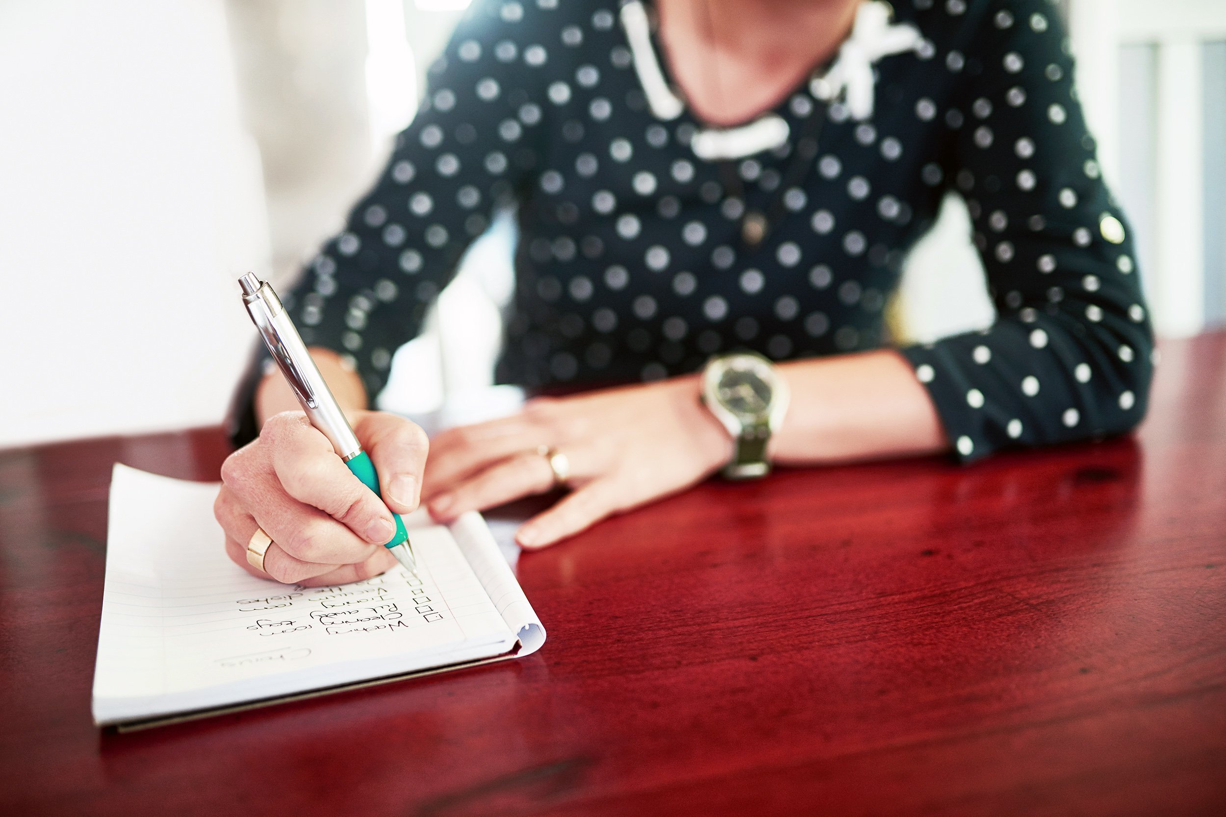 Woman taking notes sitting at a wooden table