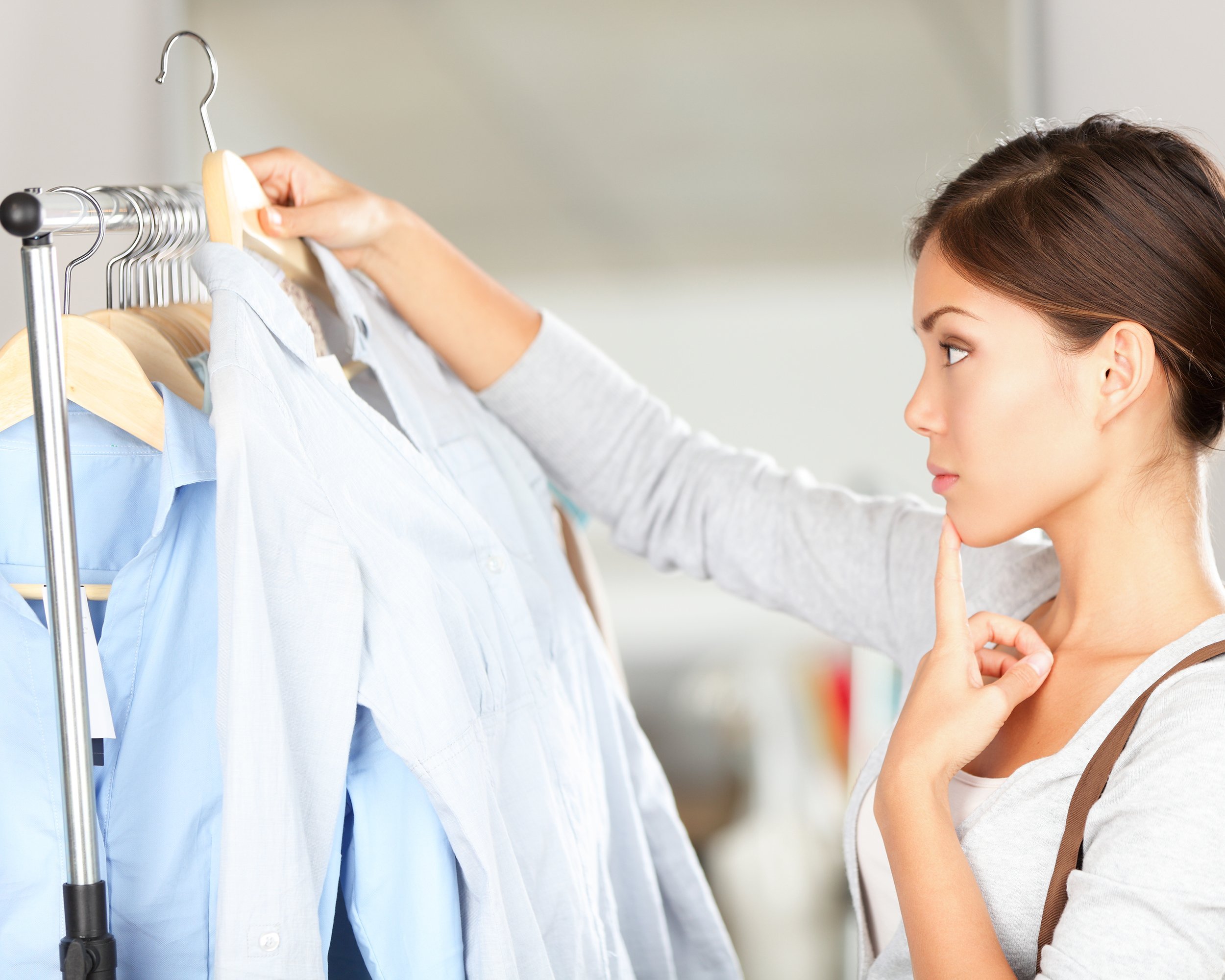shopper woman choosing clothes thinking looking at clothing while shopping in store