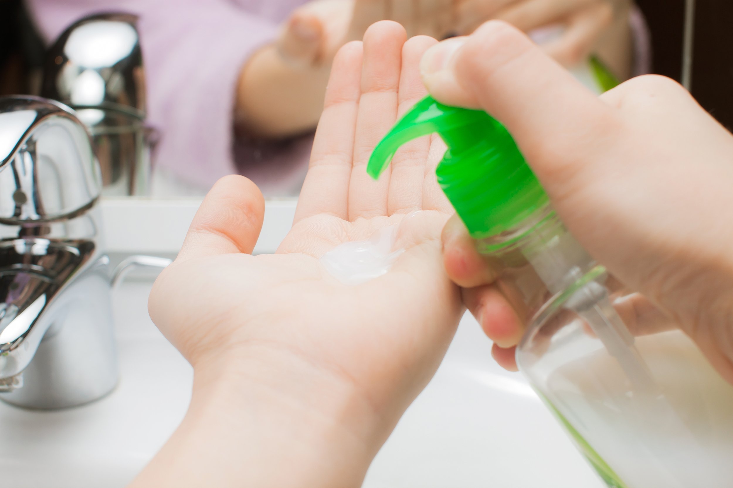 child washing hands with hand sanitizer