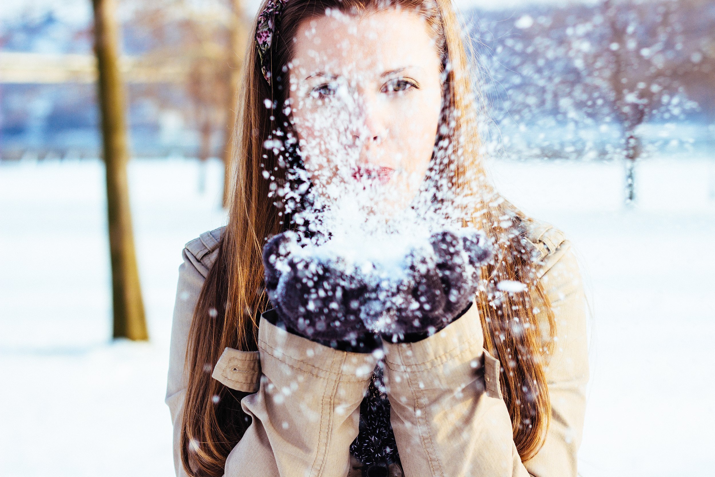 woman blowing snow out of hand in the outdoors during winter