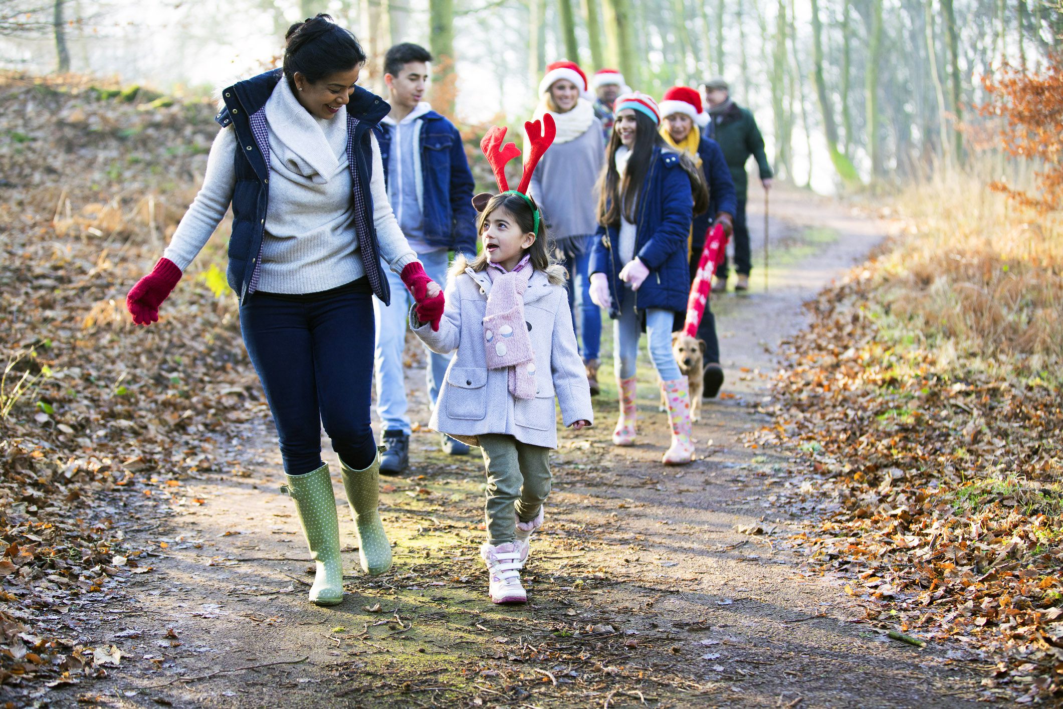 family taking walk through woods during christmas time, wearing christmas accessories