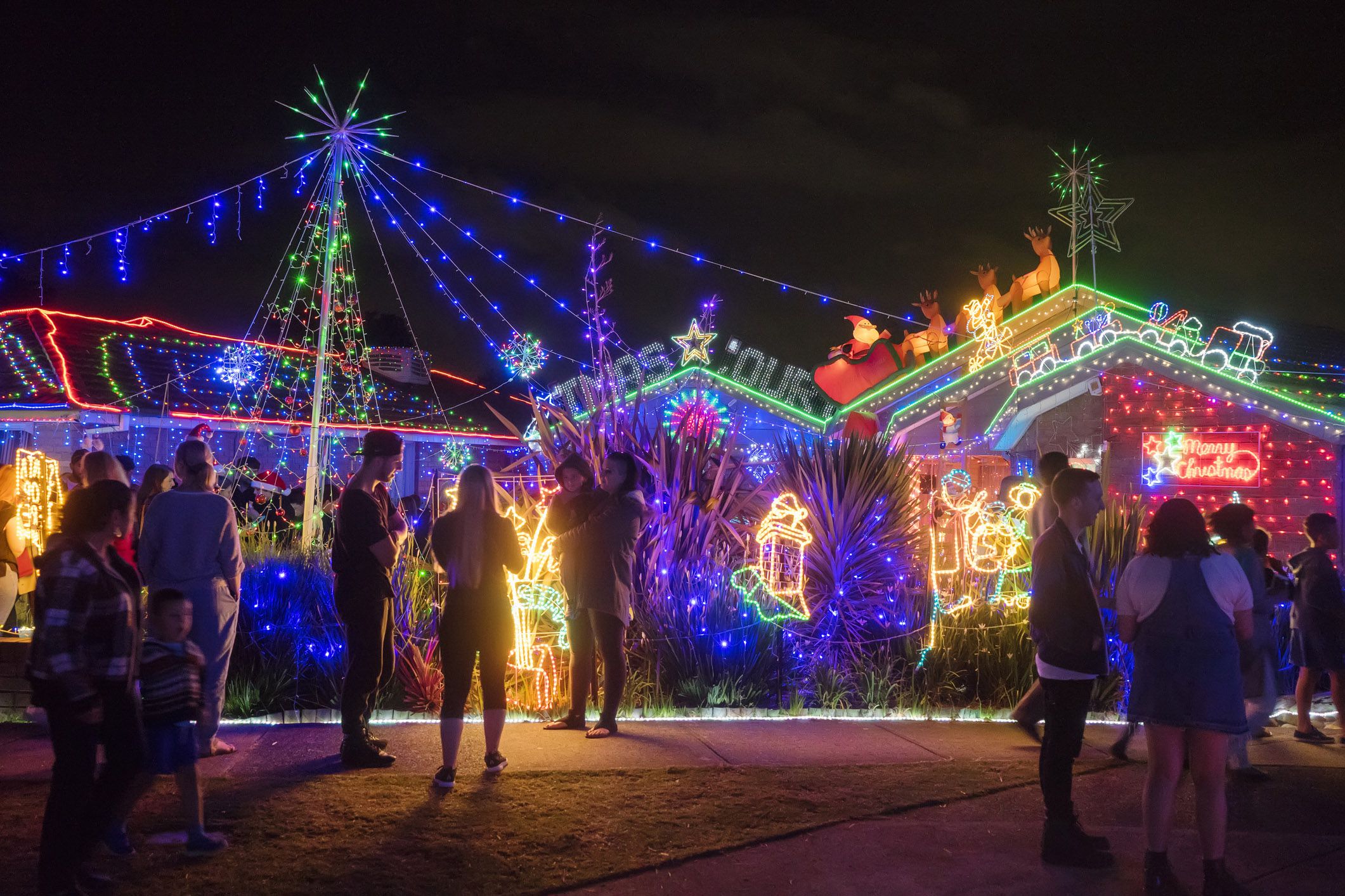 people walking around christmas lights neighborhood display