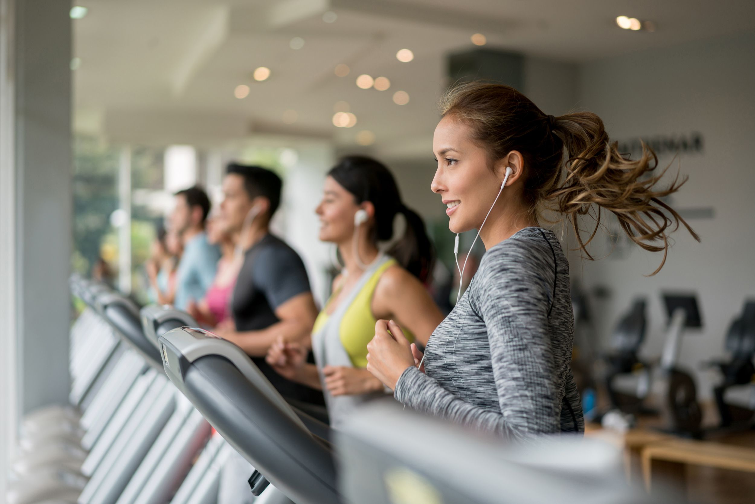 people exercising at the gym running on a treadmill