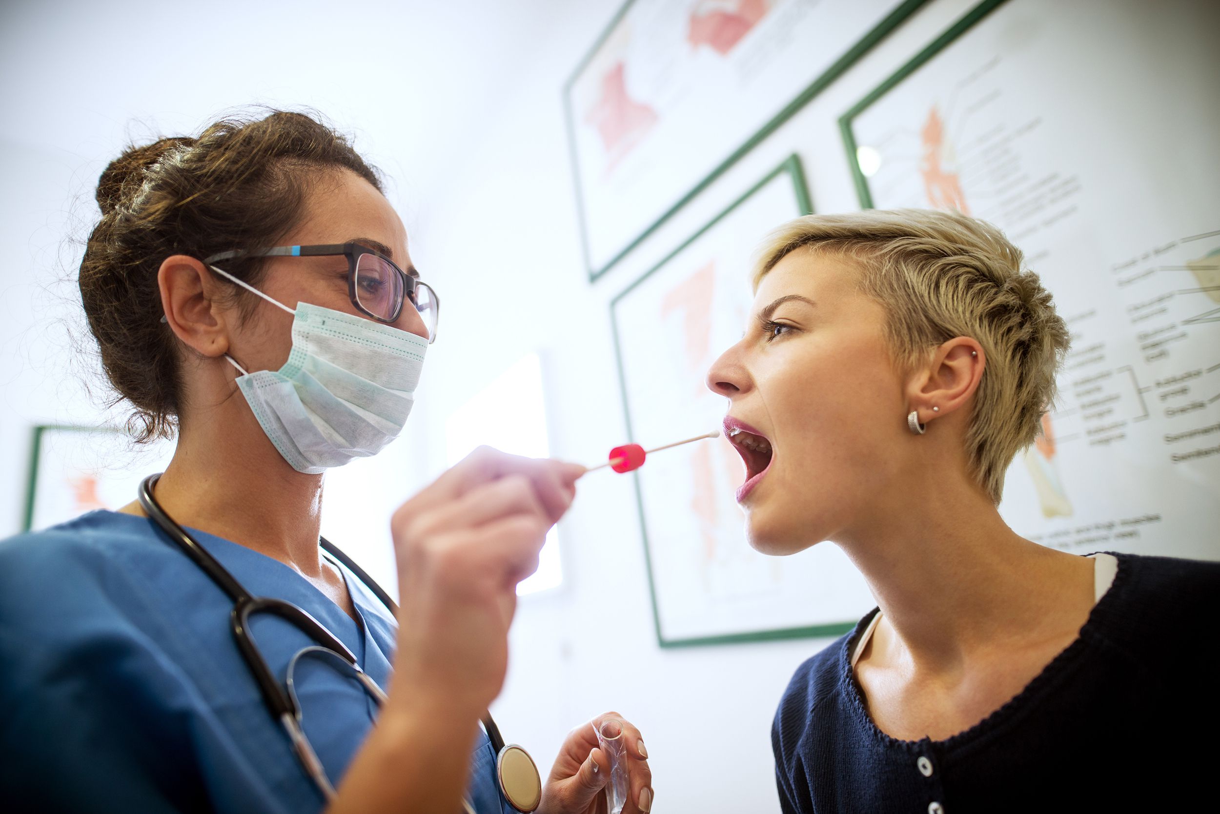 doctor holding buccal cotton swab and test tube ready to collect DNA from the cells on the inside of a woman patient