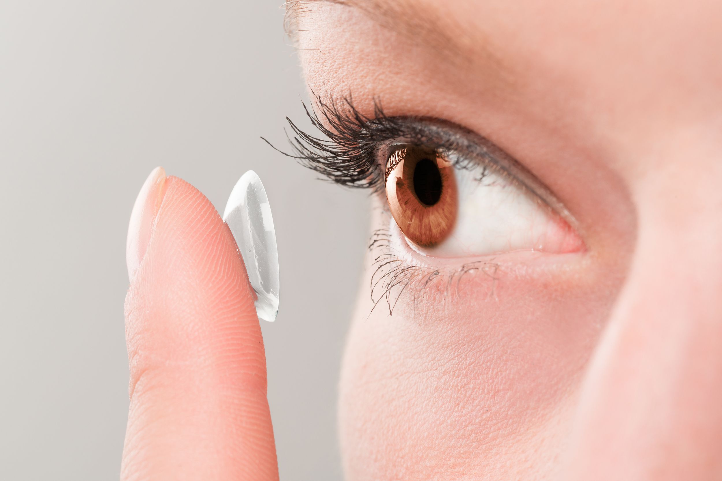 woman inserting a contact lens in eye