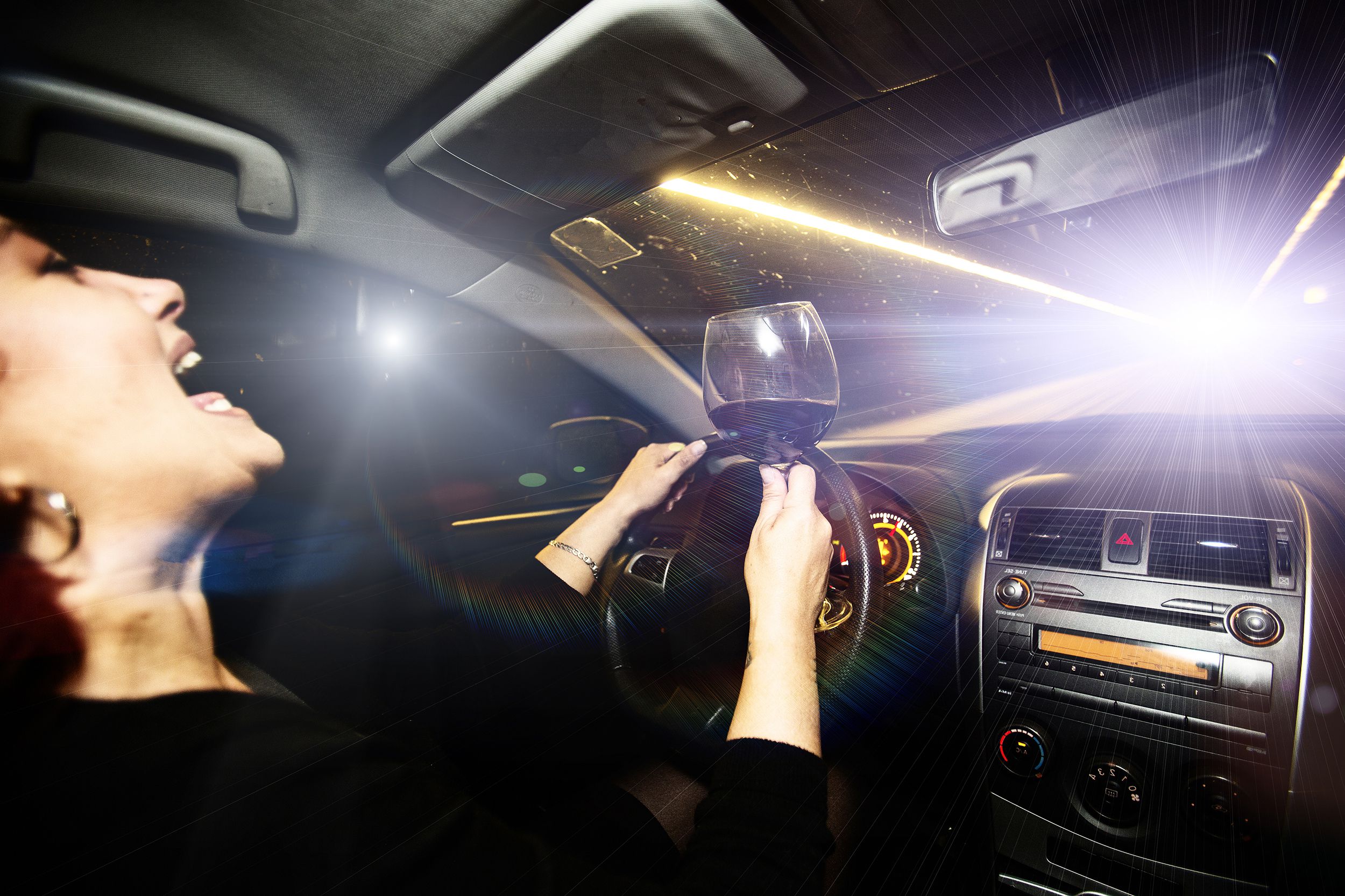 motor vehicle driver drives a car holding a glass of wine