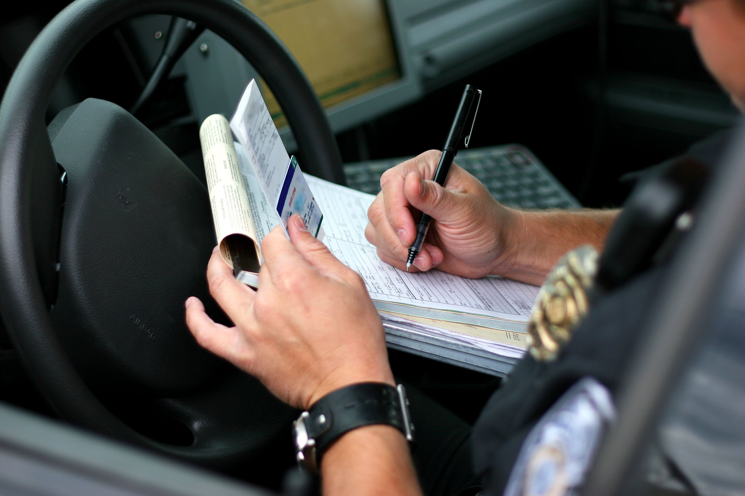 police writing speeding ticket in police car