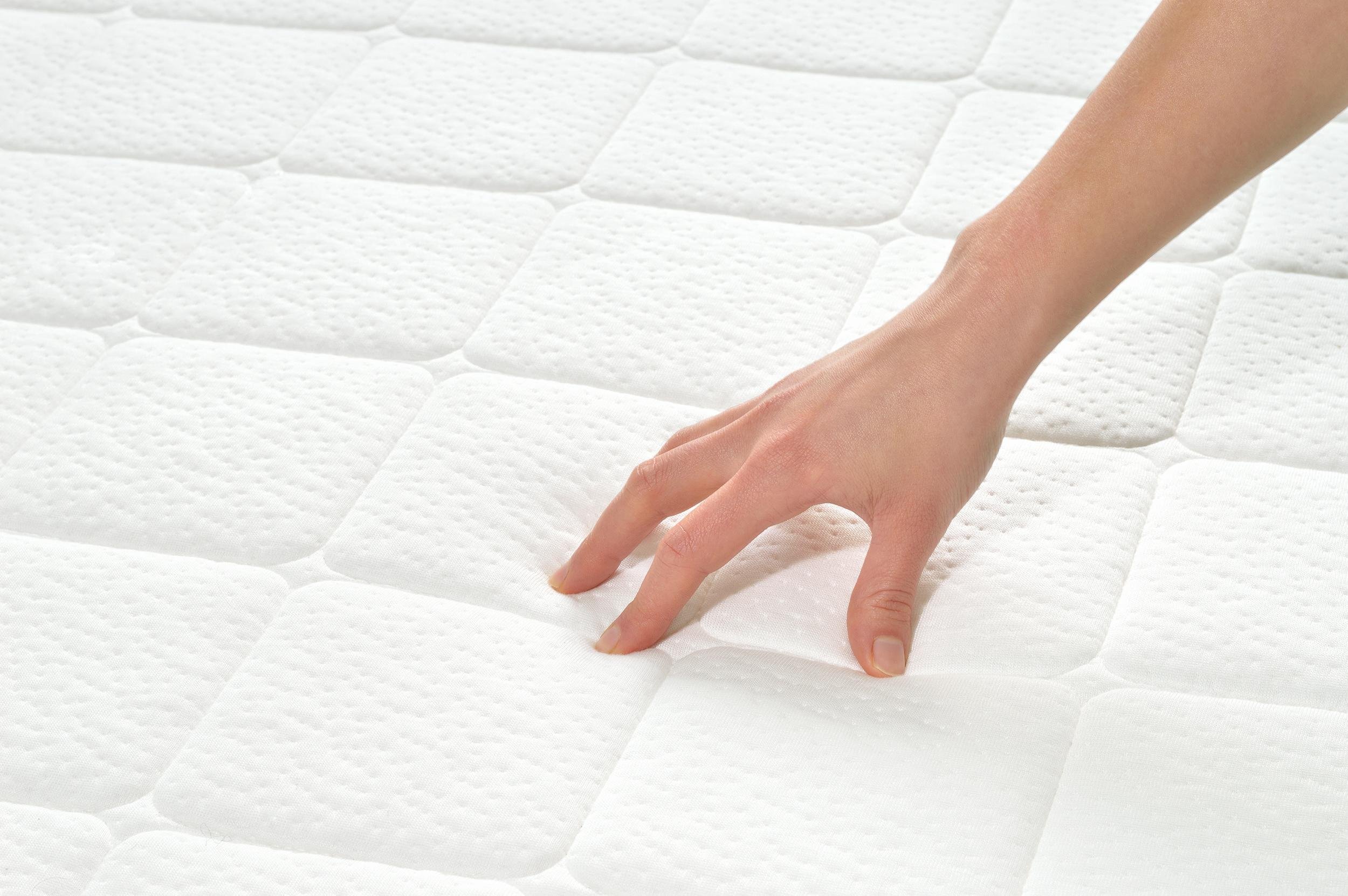 female hand touching and testing mattress in a store