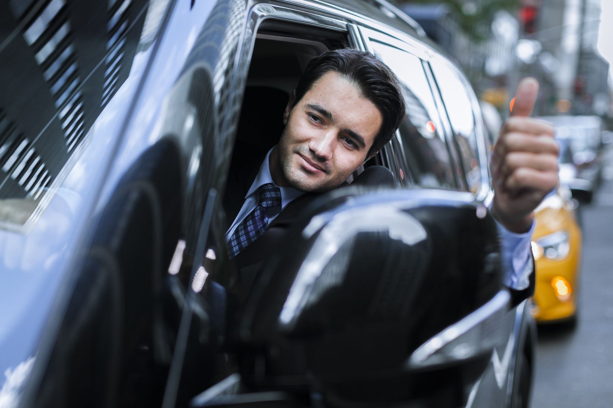 man in suit waving goodbye from car
