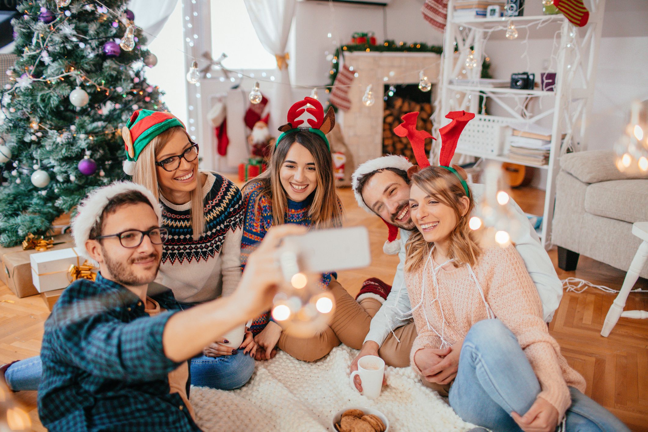 happy friends taking selfie in front of christmas decorations at home