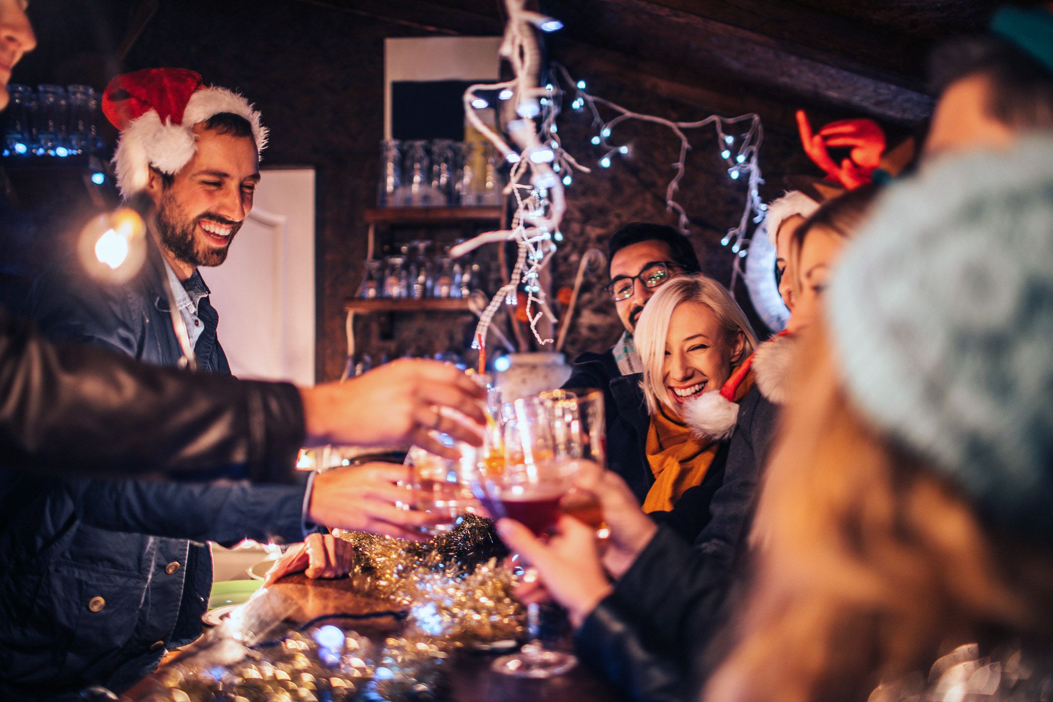 christmas party with friends in santa hats toasting with wine over table