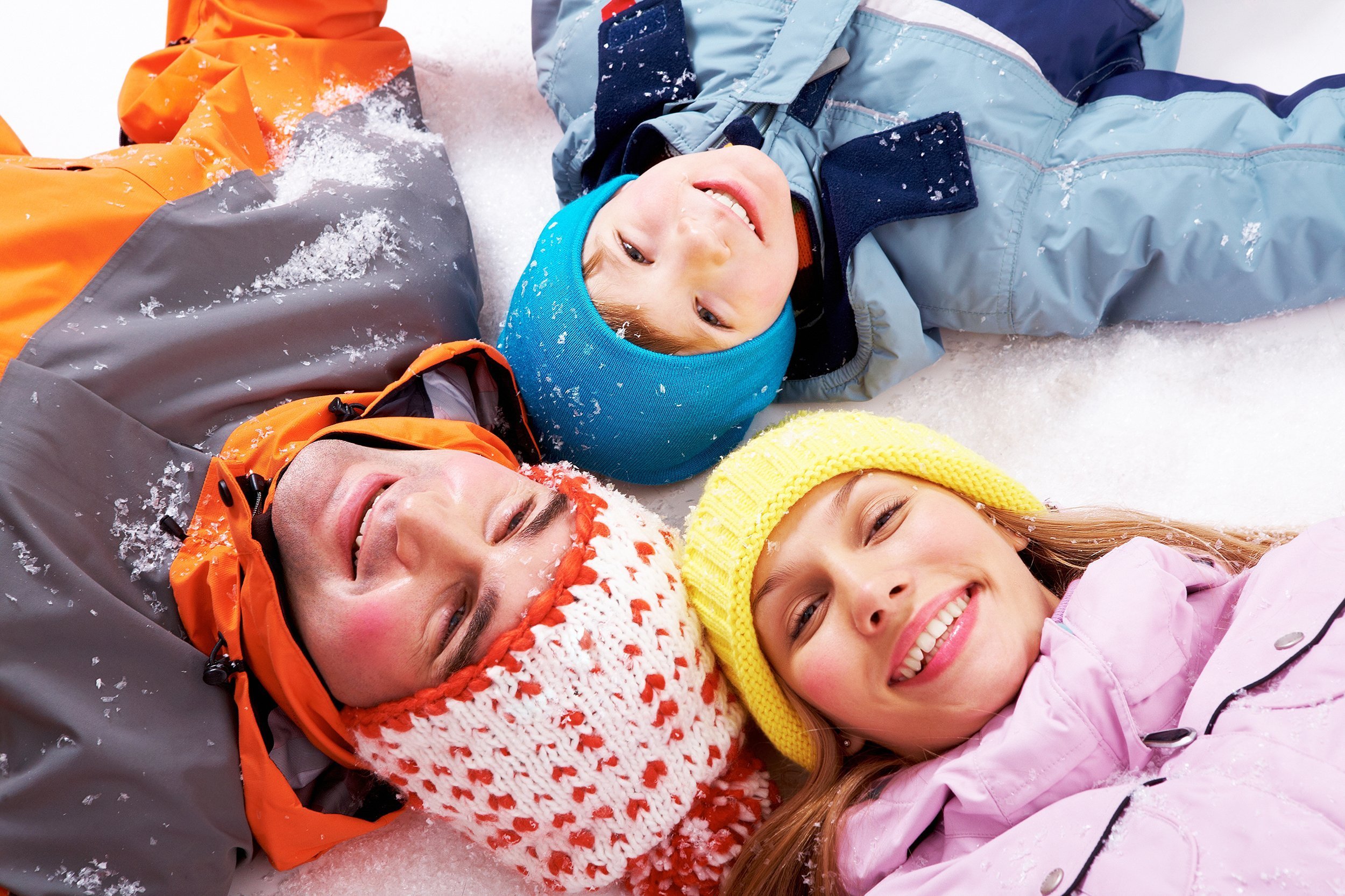 happy family in the snow while looking at camera