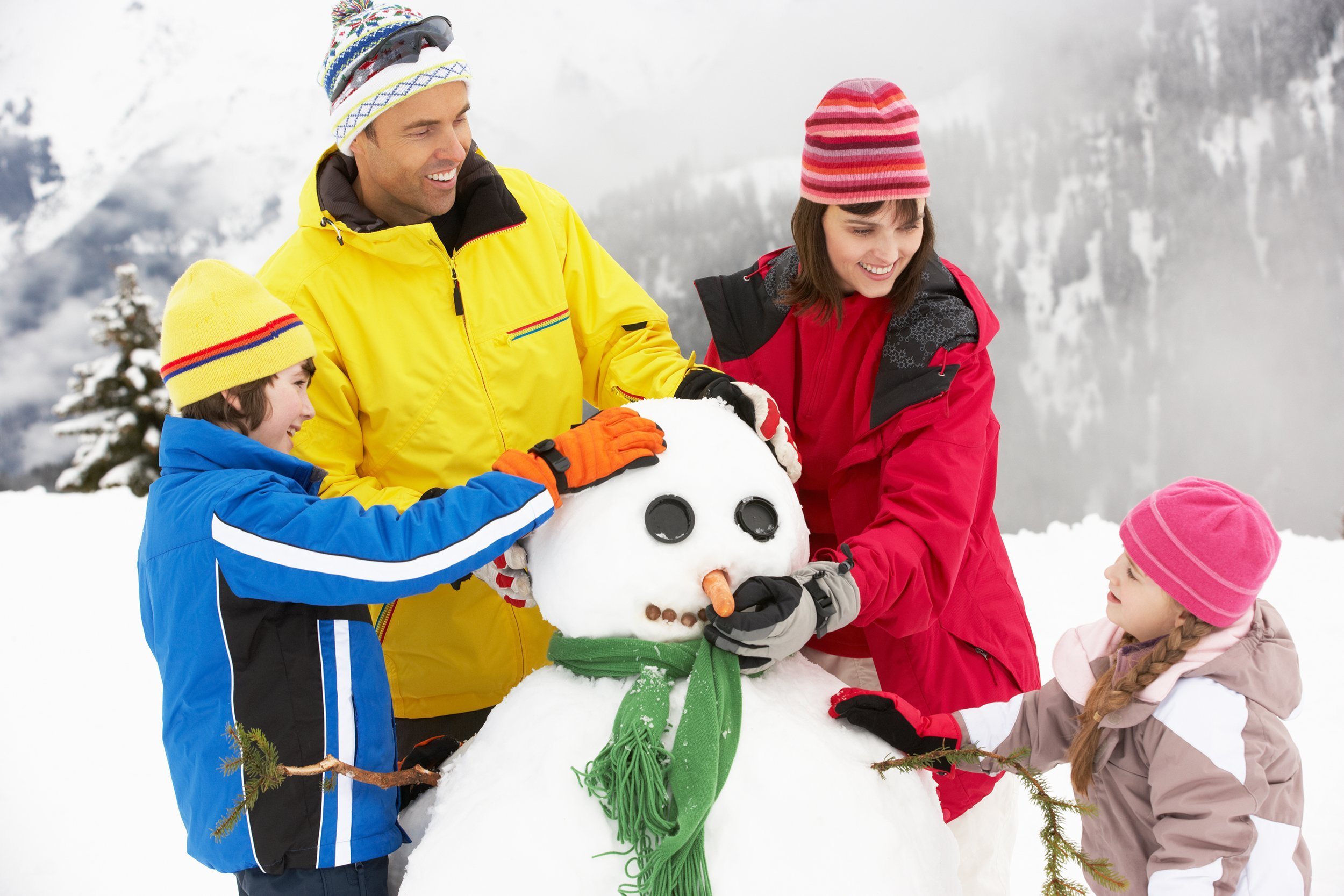 family building snowman on ski holiday in mountains