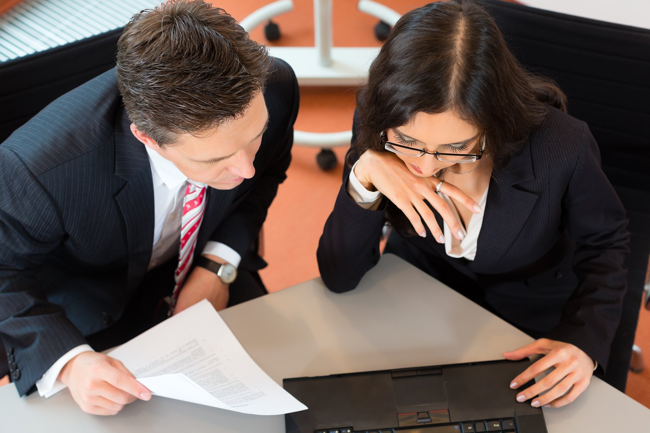 businesspeople sitting at office desk with a document and laptop