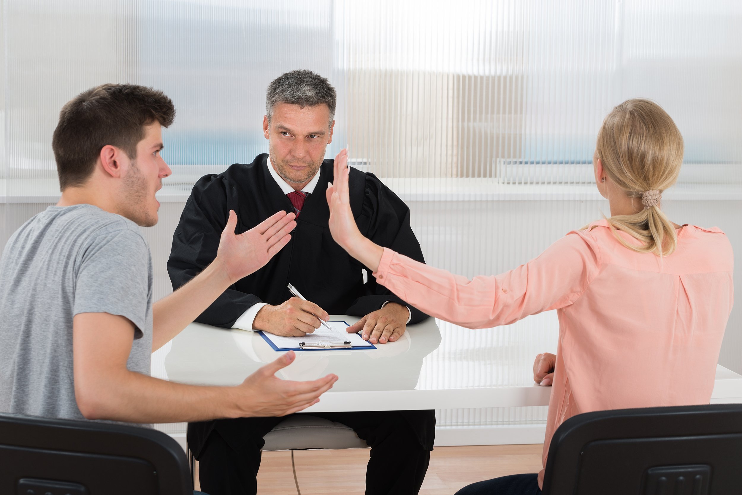 young couple having an argument in front of male judge at desk